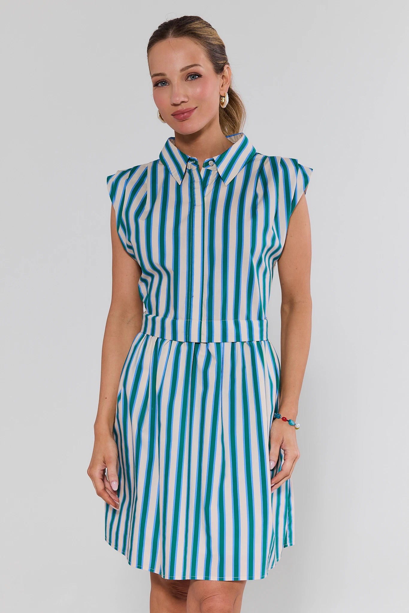 Woman wearing a green and white striped dress on a plain background