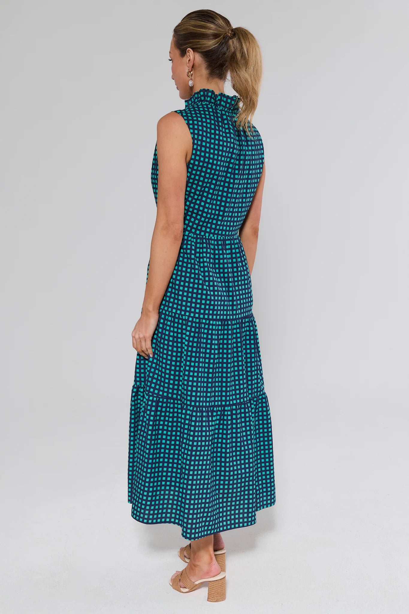 Woman wearing a teal patterned dress on a white background