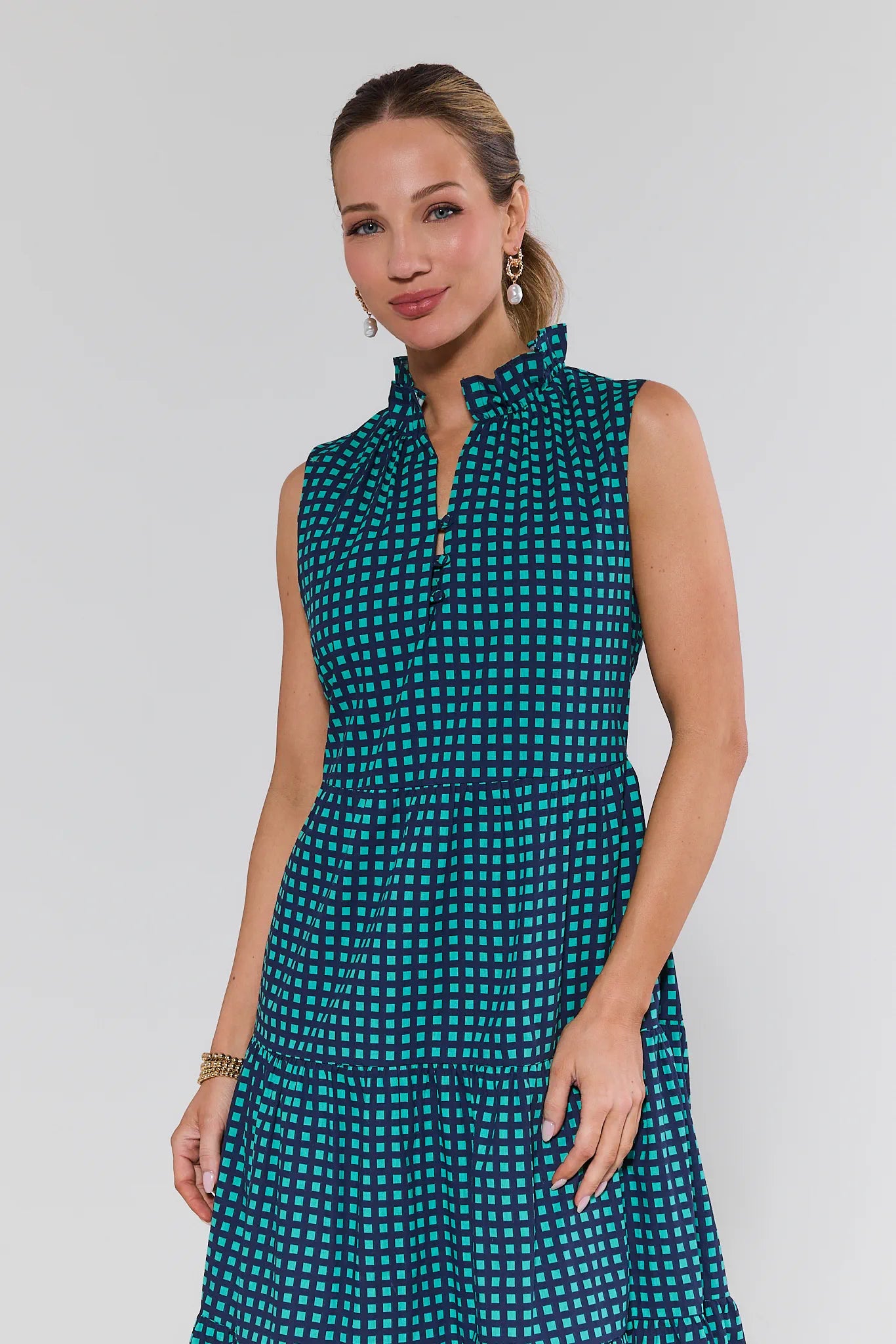 Woman wearing a teal patterned dress against a plain background