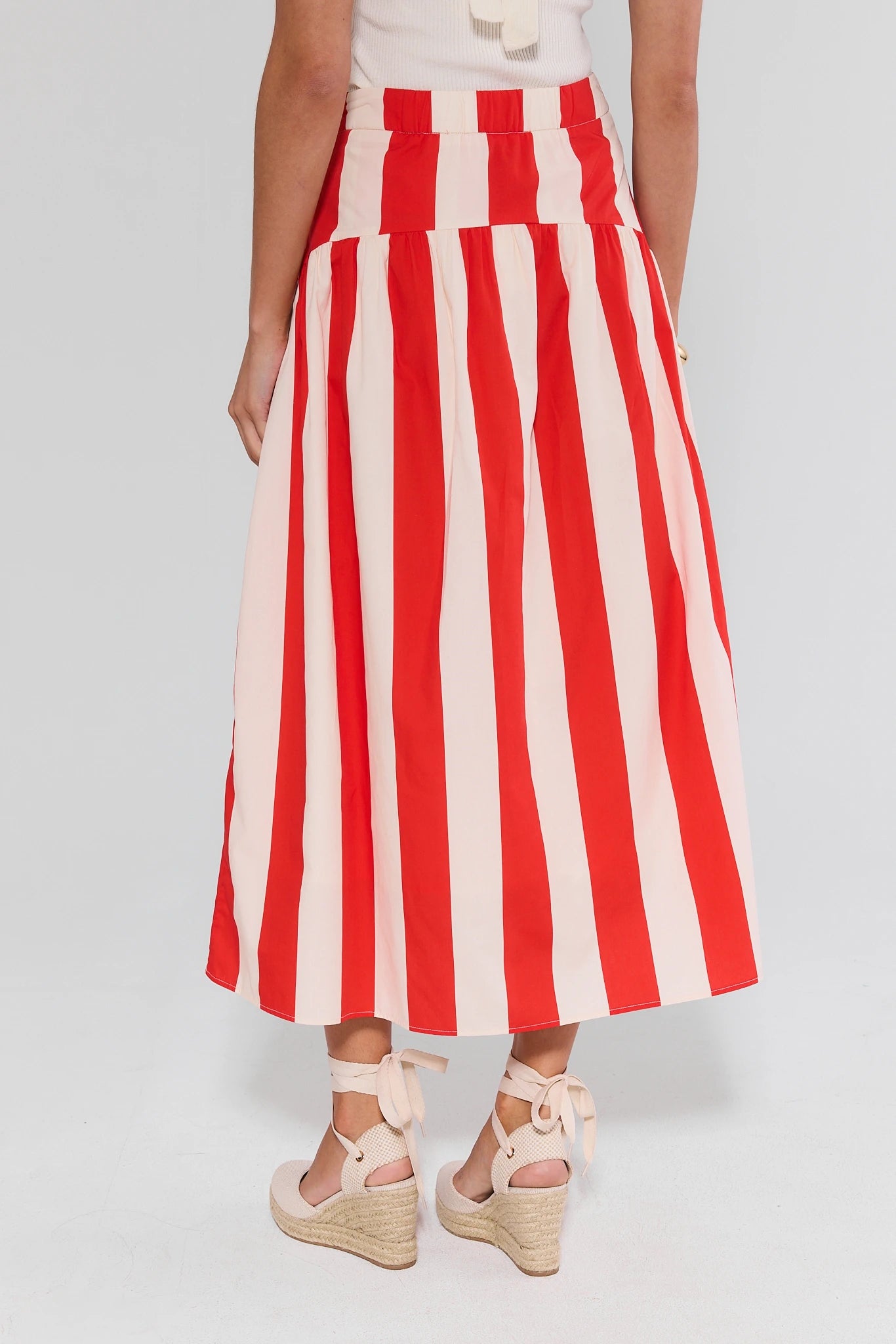 Red and white striped skirt worn by a person on a plain background