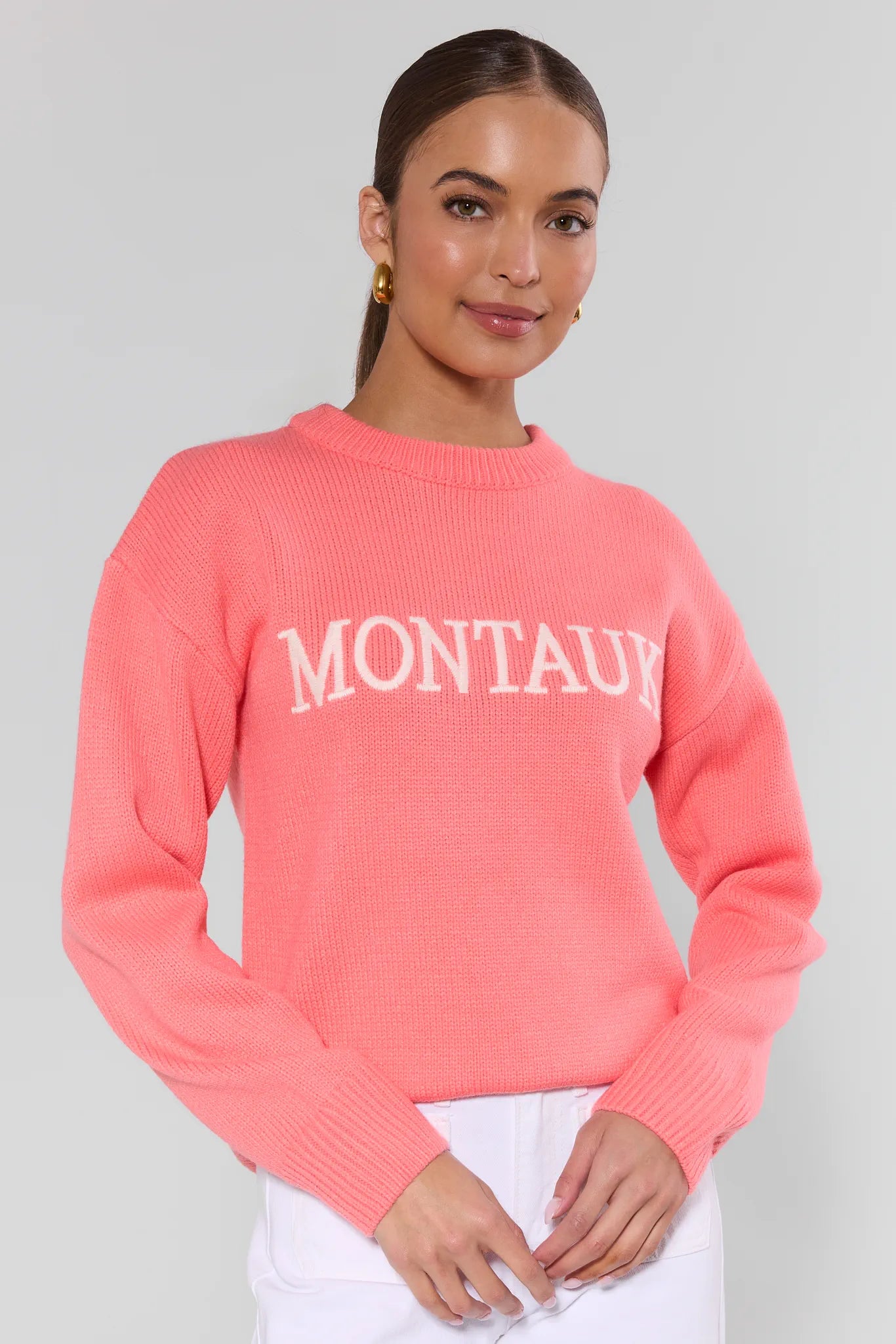 Woman wearing a pink sweater with 'MONTAUP' text on a gray background