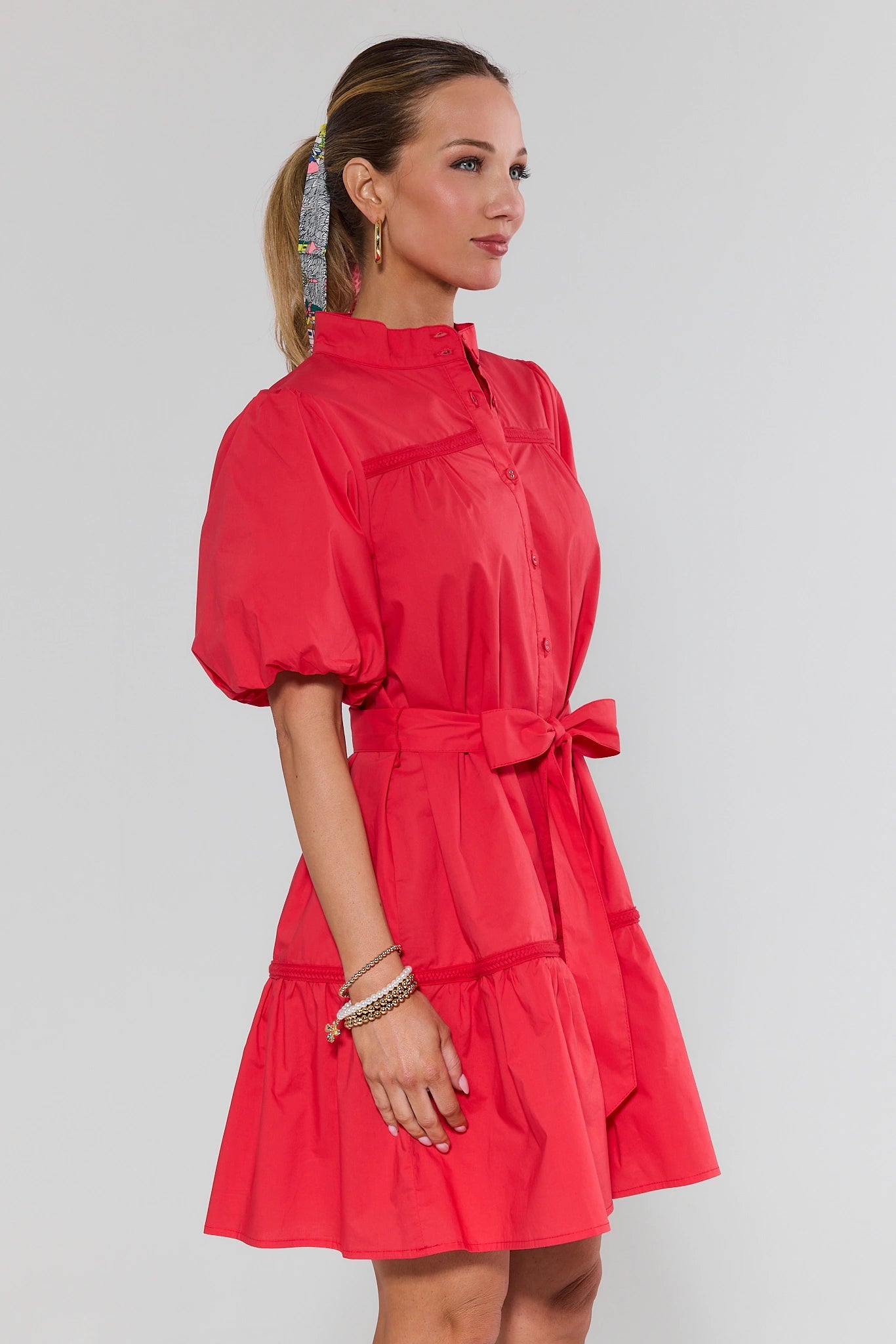 Woman wearing a red dress with puff sleeves against a gray background