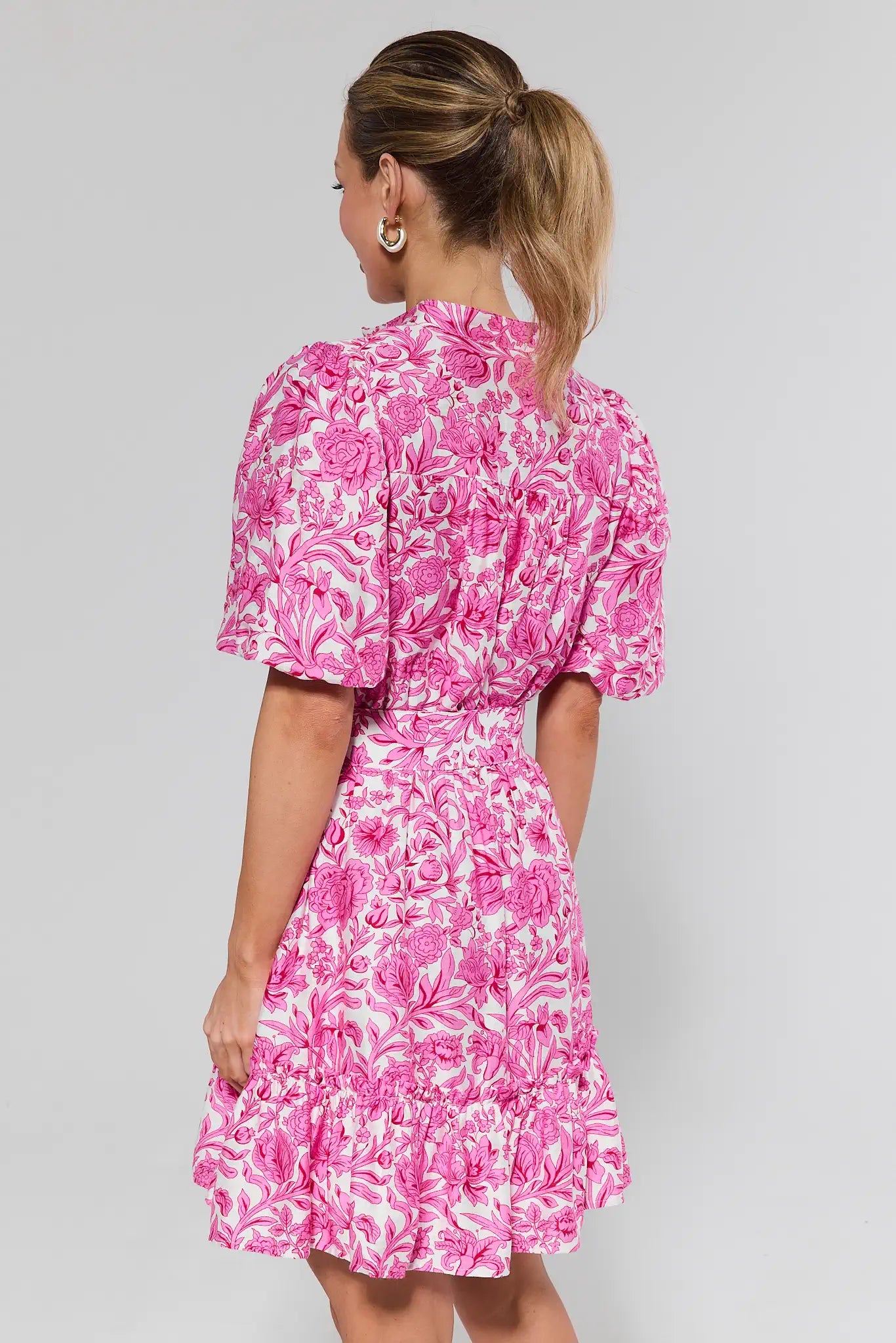 Woman wearing a pink floral dress against a gray background