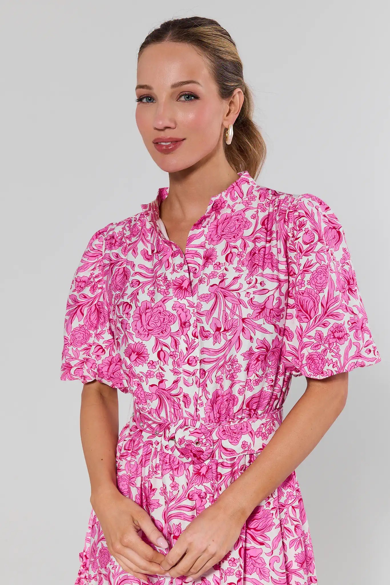 Woman wearing a pink floral dress against a plain background