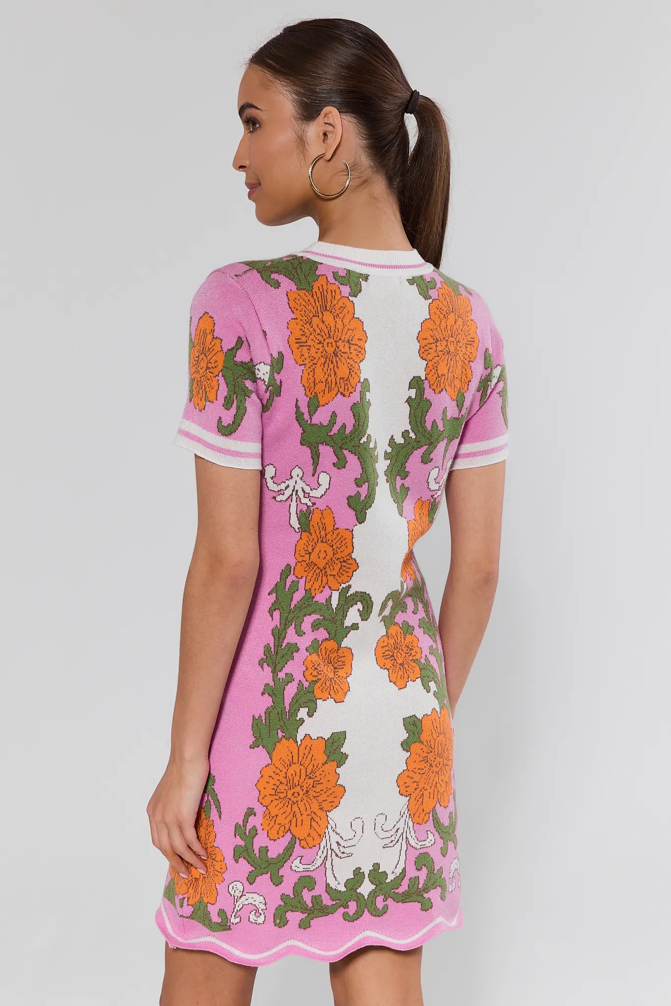 Woman wearing a floral dress with pink trim on a white background