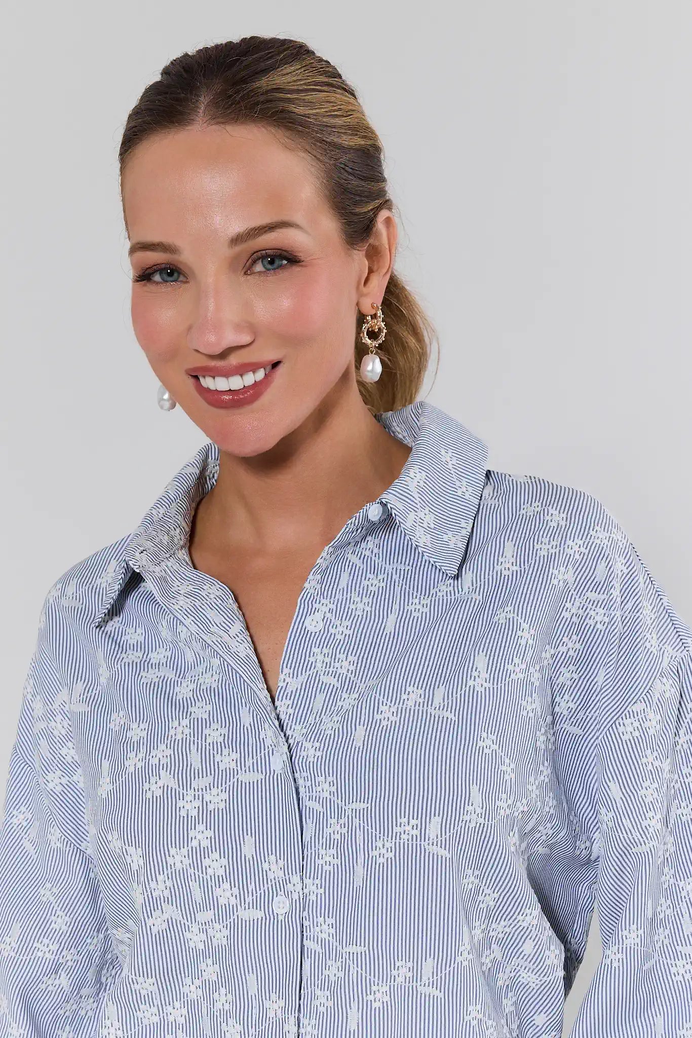 Woman wearing a blue floral blouse against a plain background close up