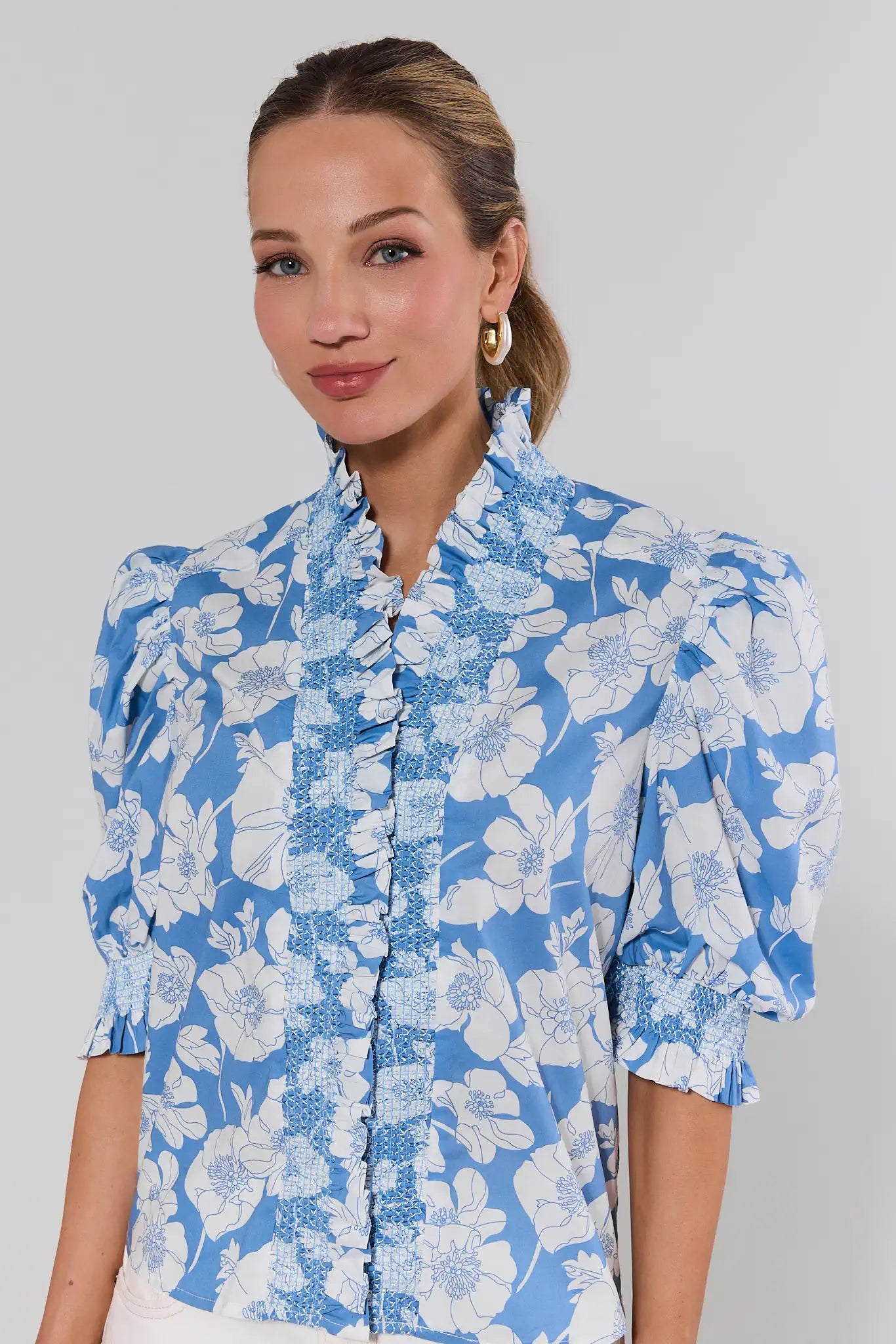 Woman wearing a blue floral blouse against a gray background