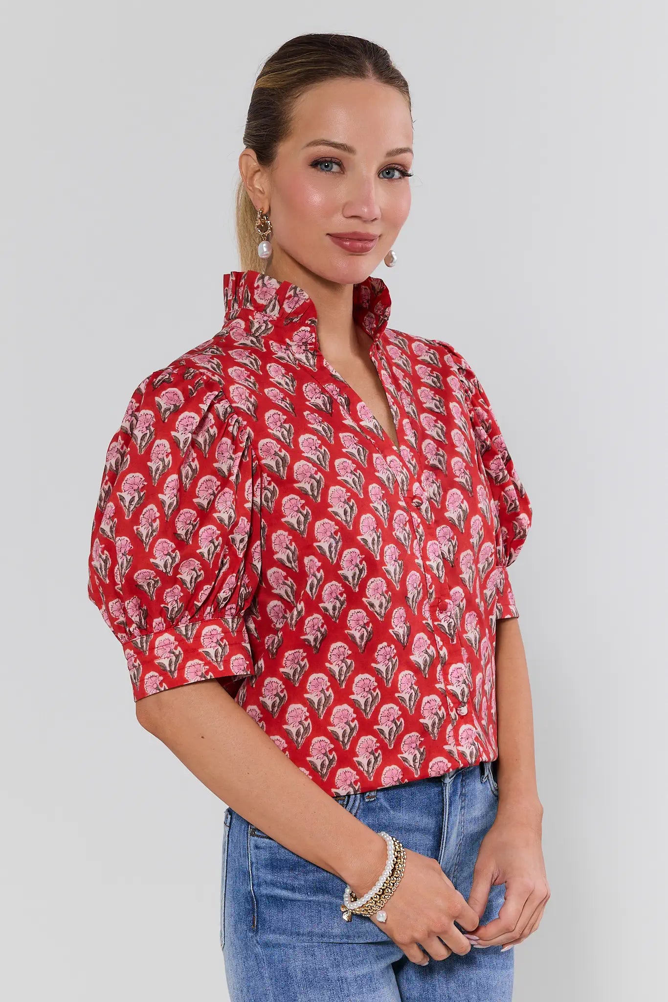 Woman wearing a red patterned blouse against a white background
