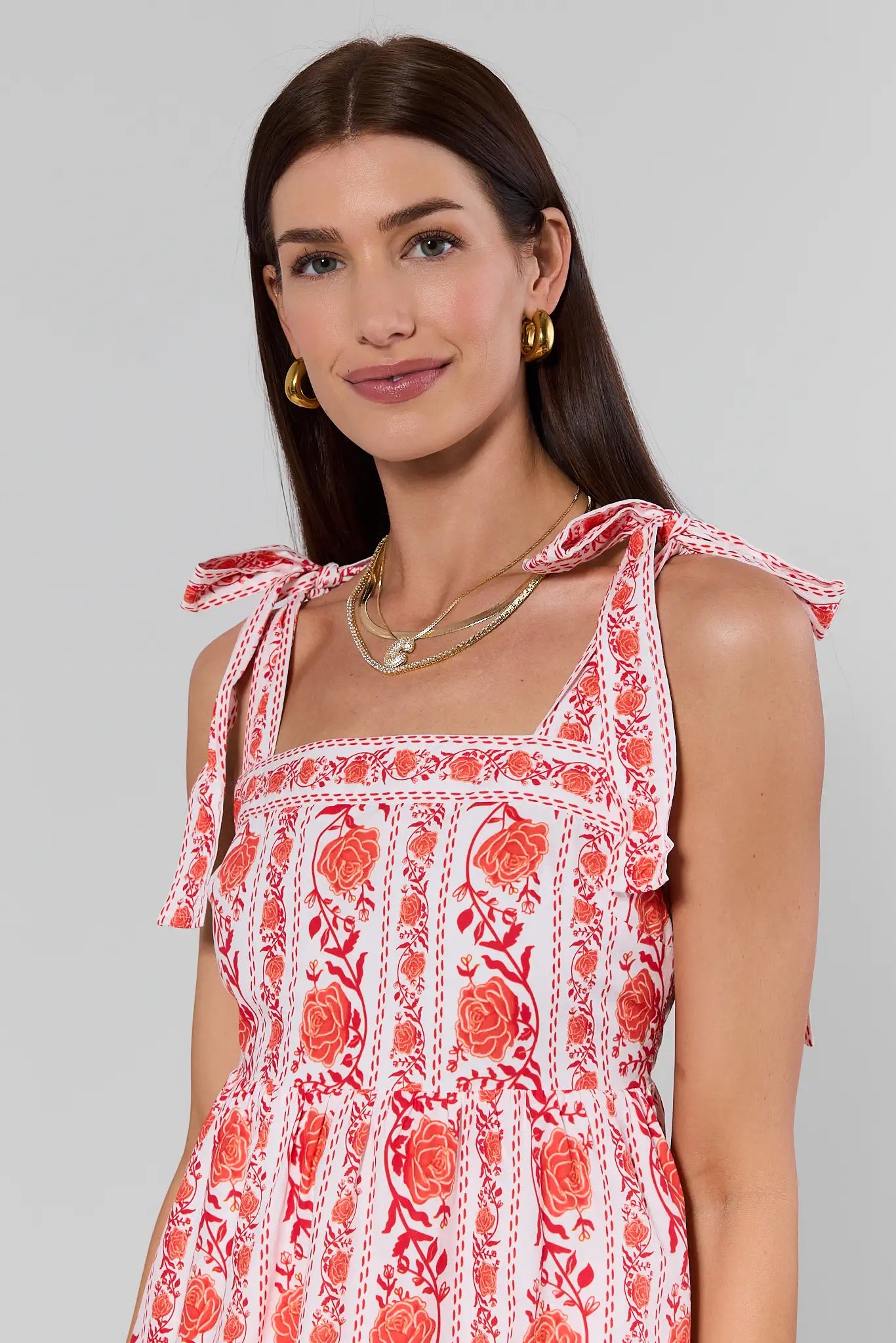 Woman wearing a red and white floral dress against a gray background