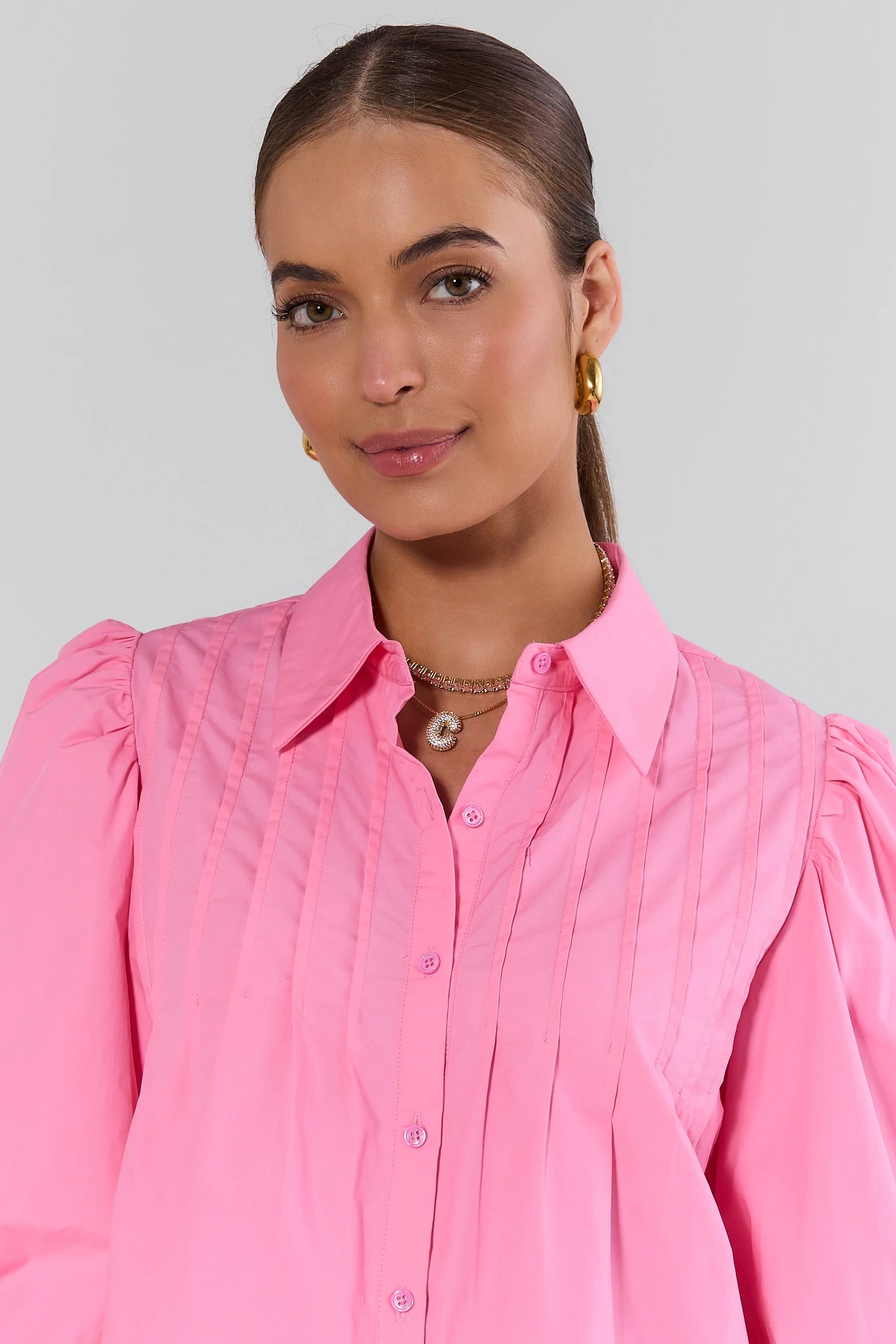 Woman wearing a pink shirt with puffed sleeves against a plain background