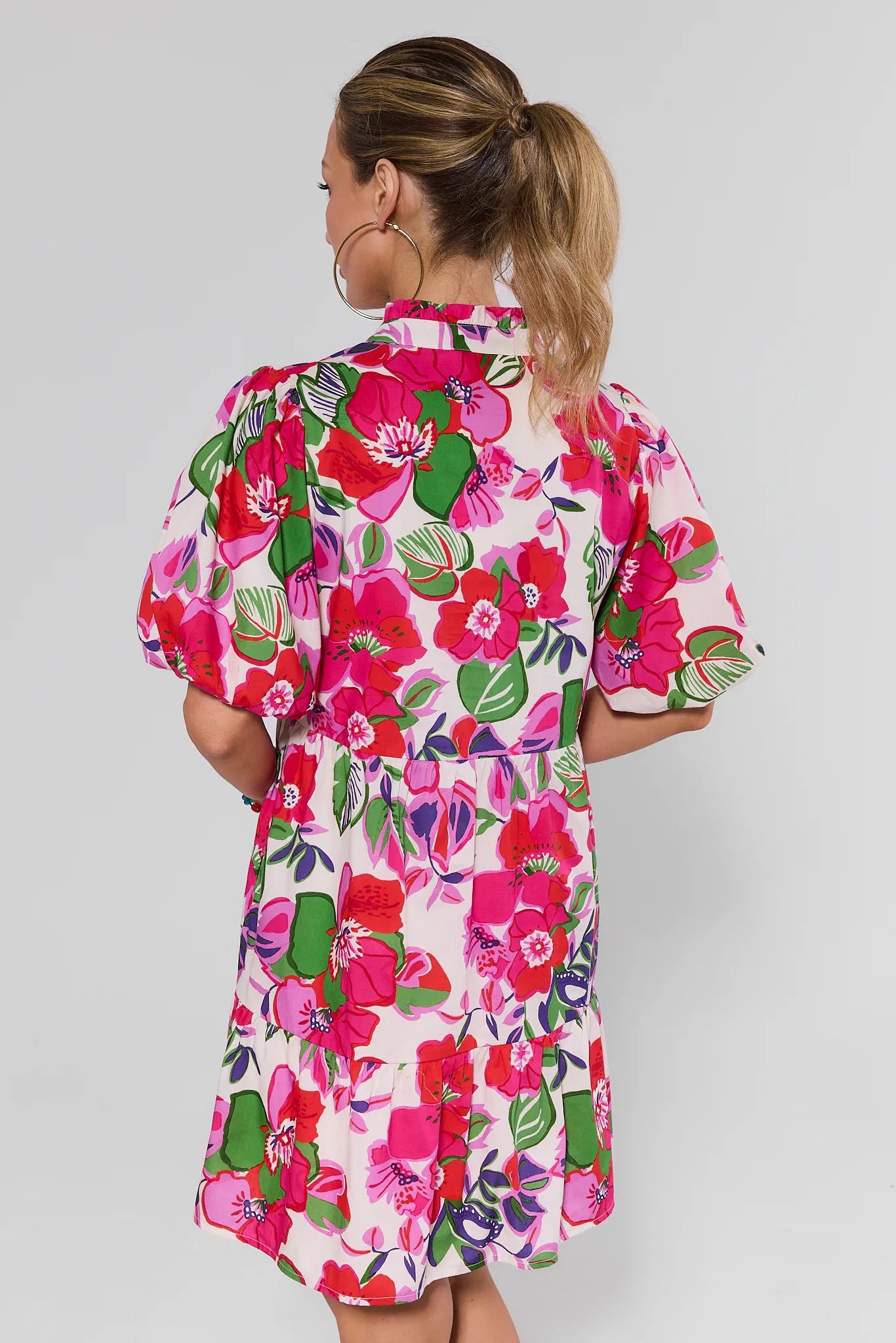 Woman wearing a colorful floral dress against a plain background