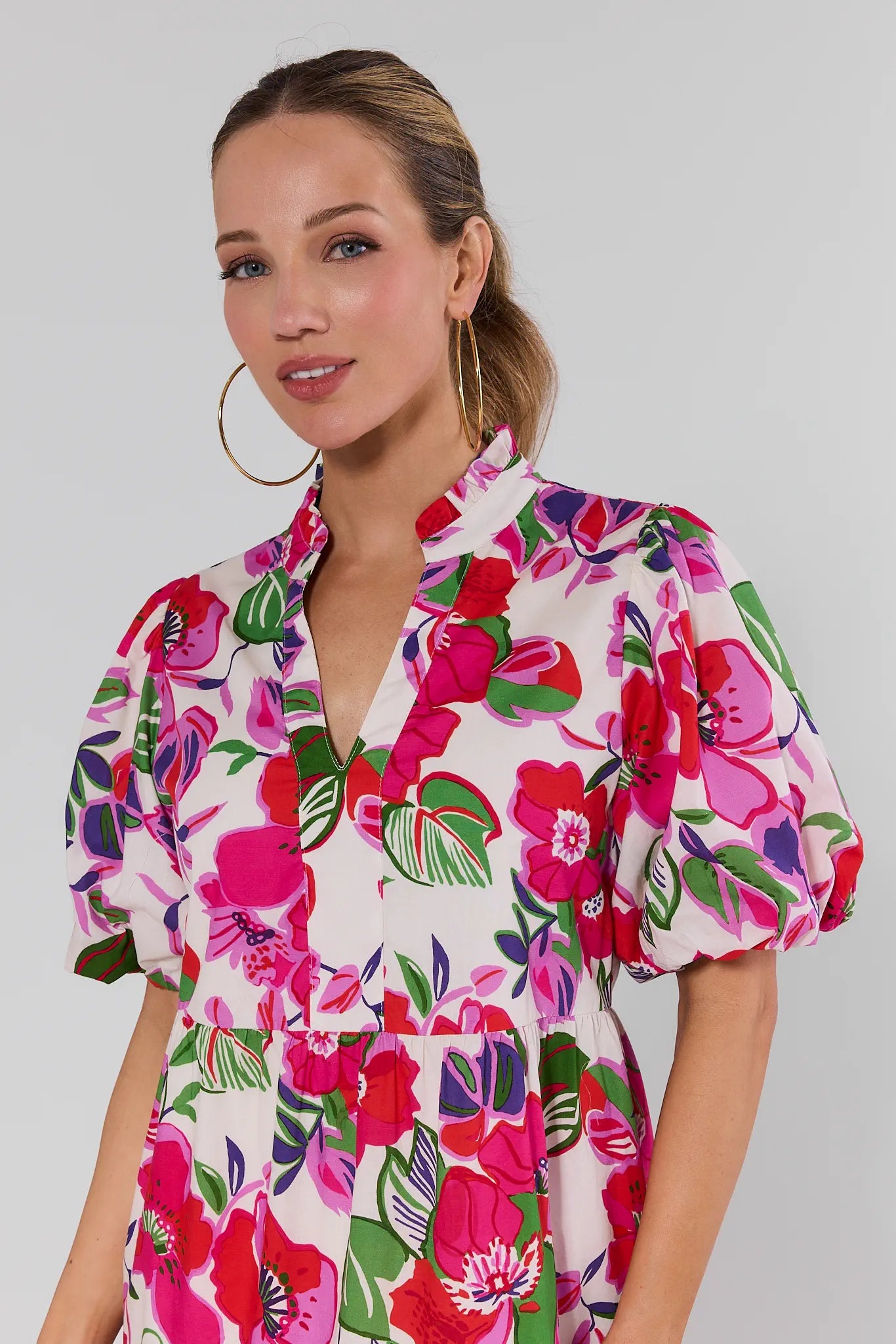Woman wearing a colorful floral dress against a plain background