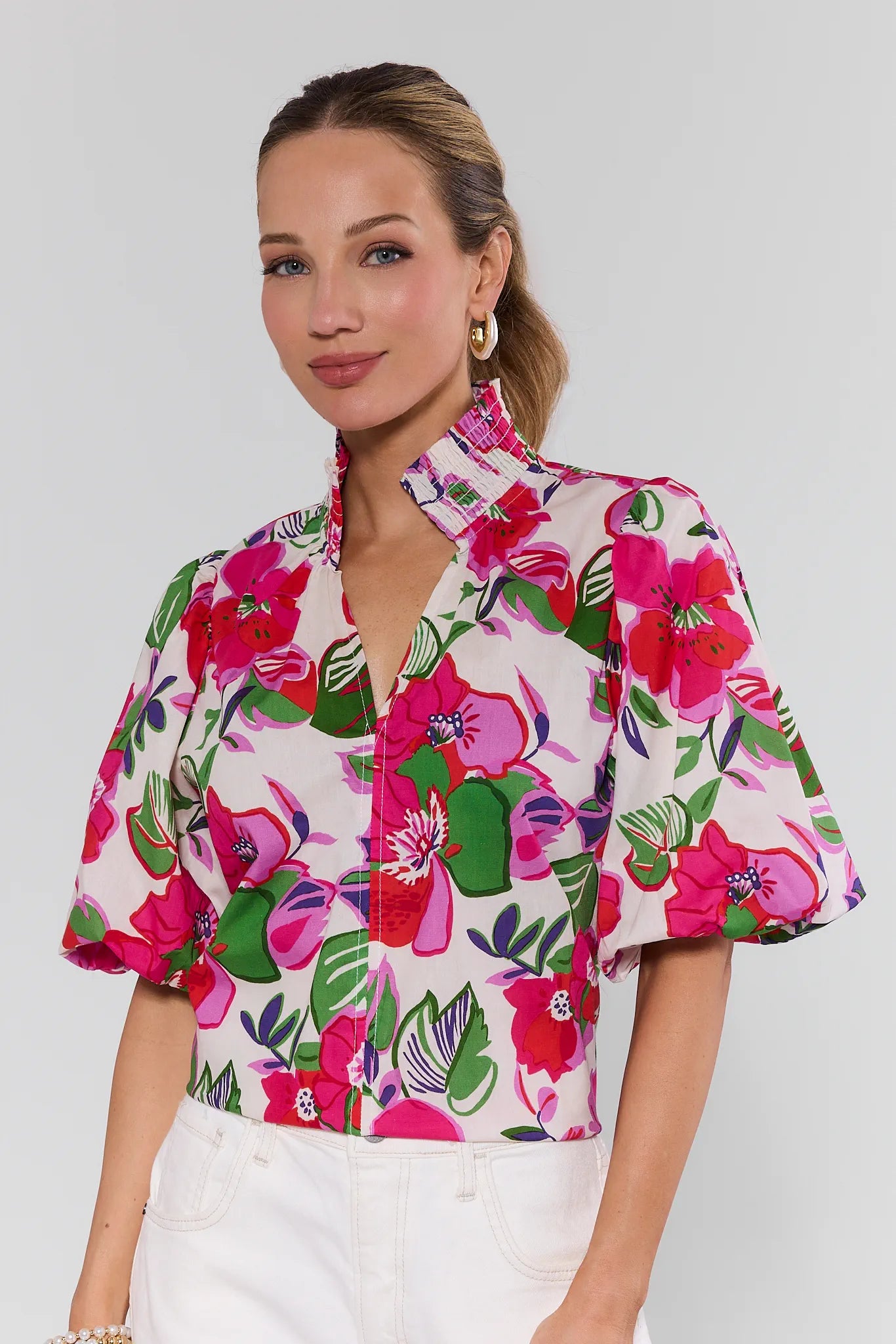 Woman wearing a colorful floral blouse against a plain background
