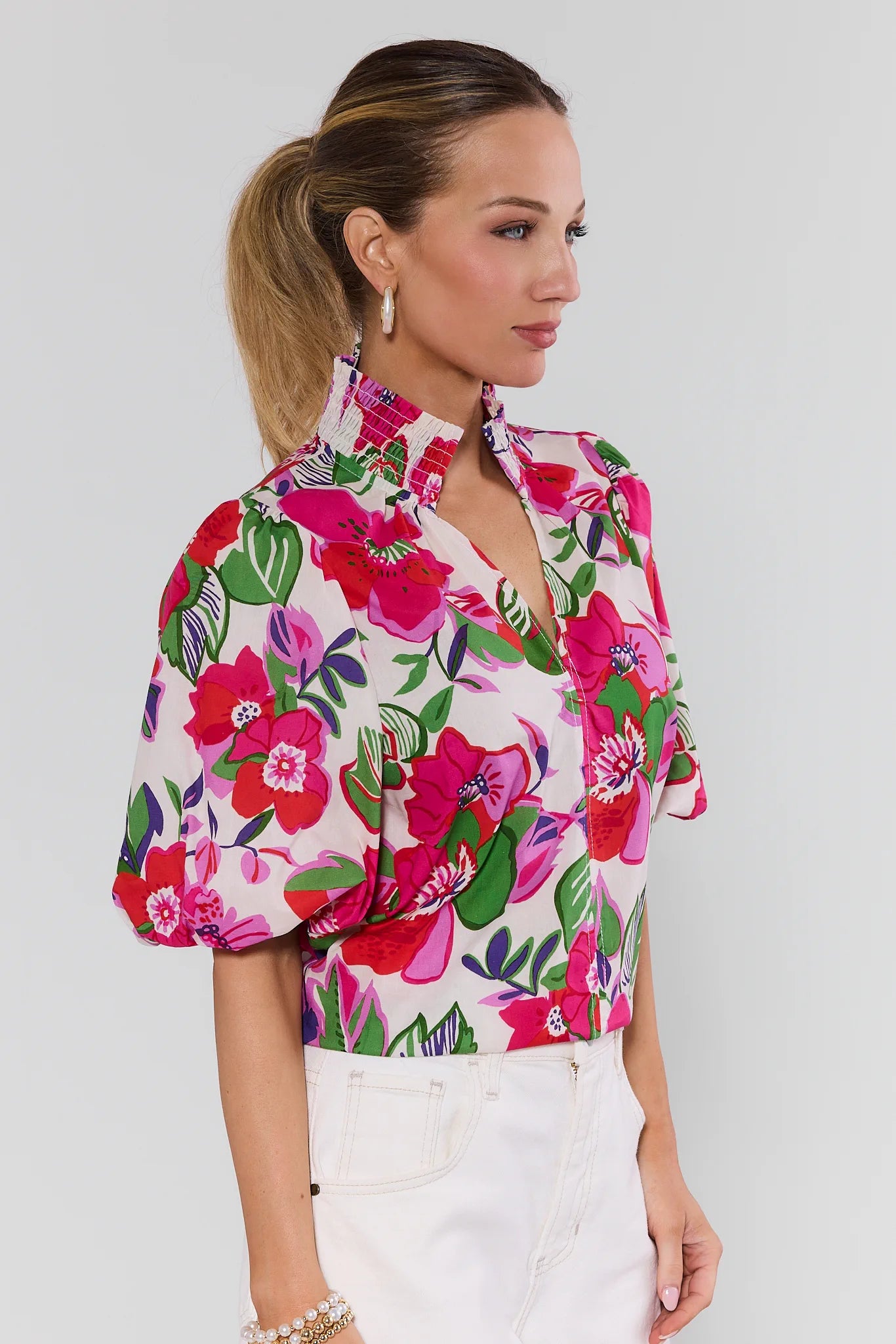 Woman wearing a colorful floral blouse against a plain background