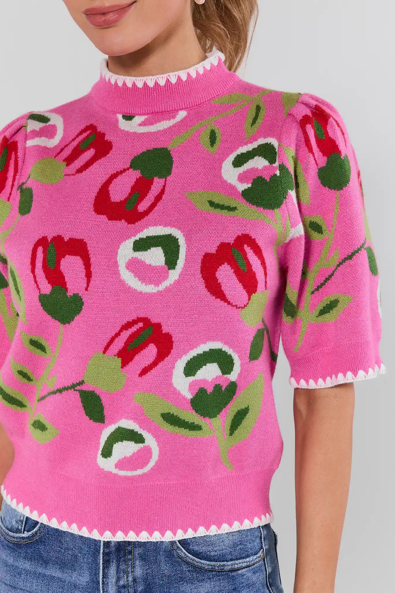 Person wearing a pink floral-patterned sweater against a plain background