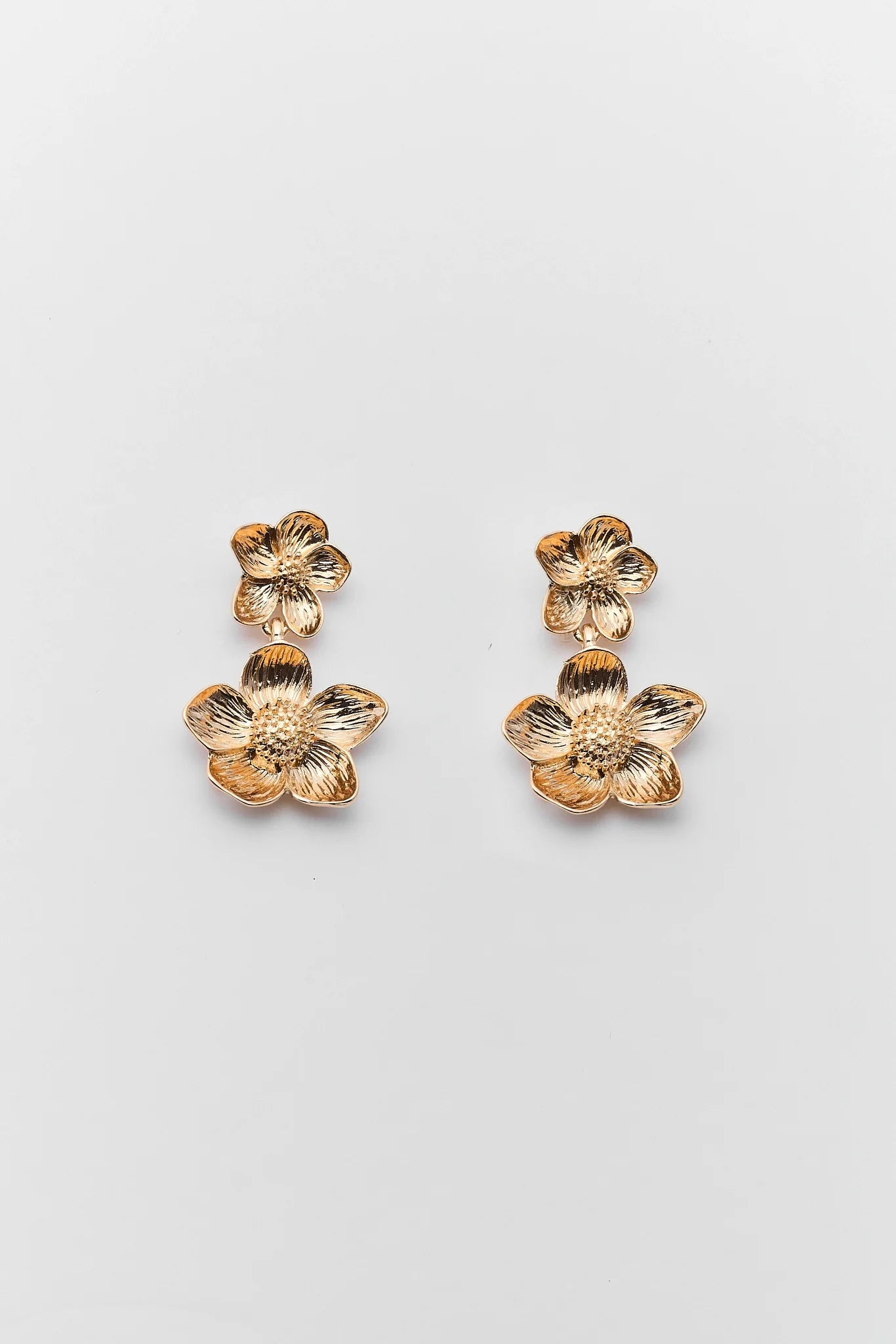 Gold floral earrings on a light gray background