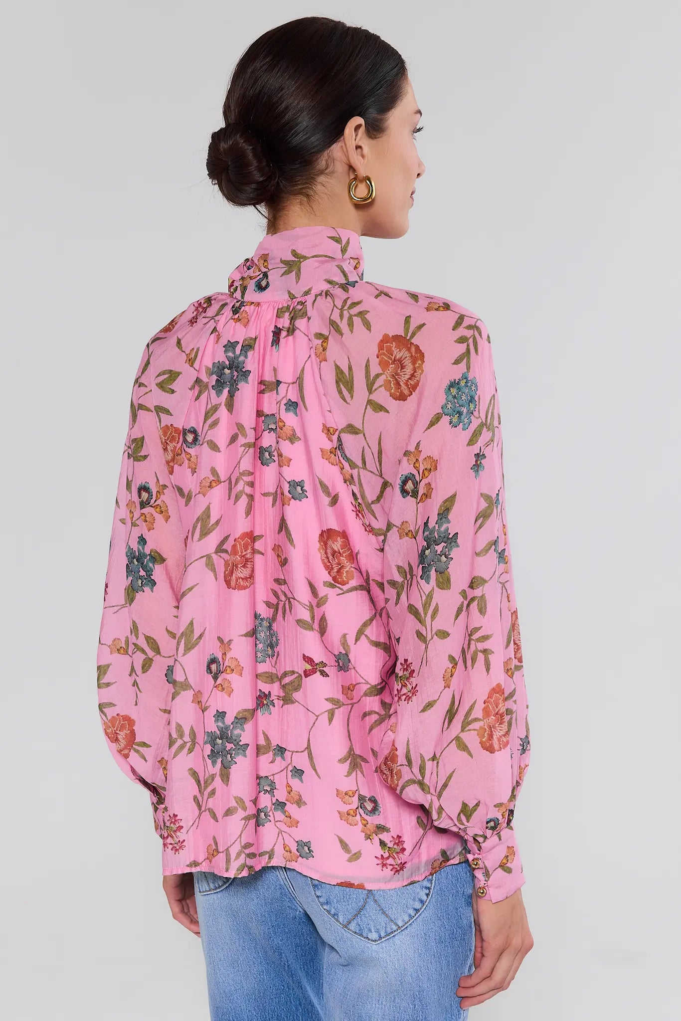 woman standing wearing long sleeve pink floral top on white background