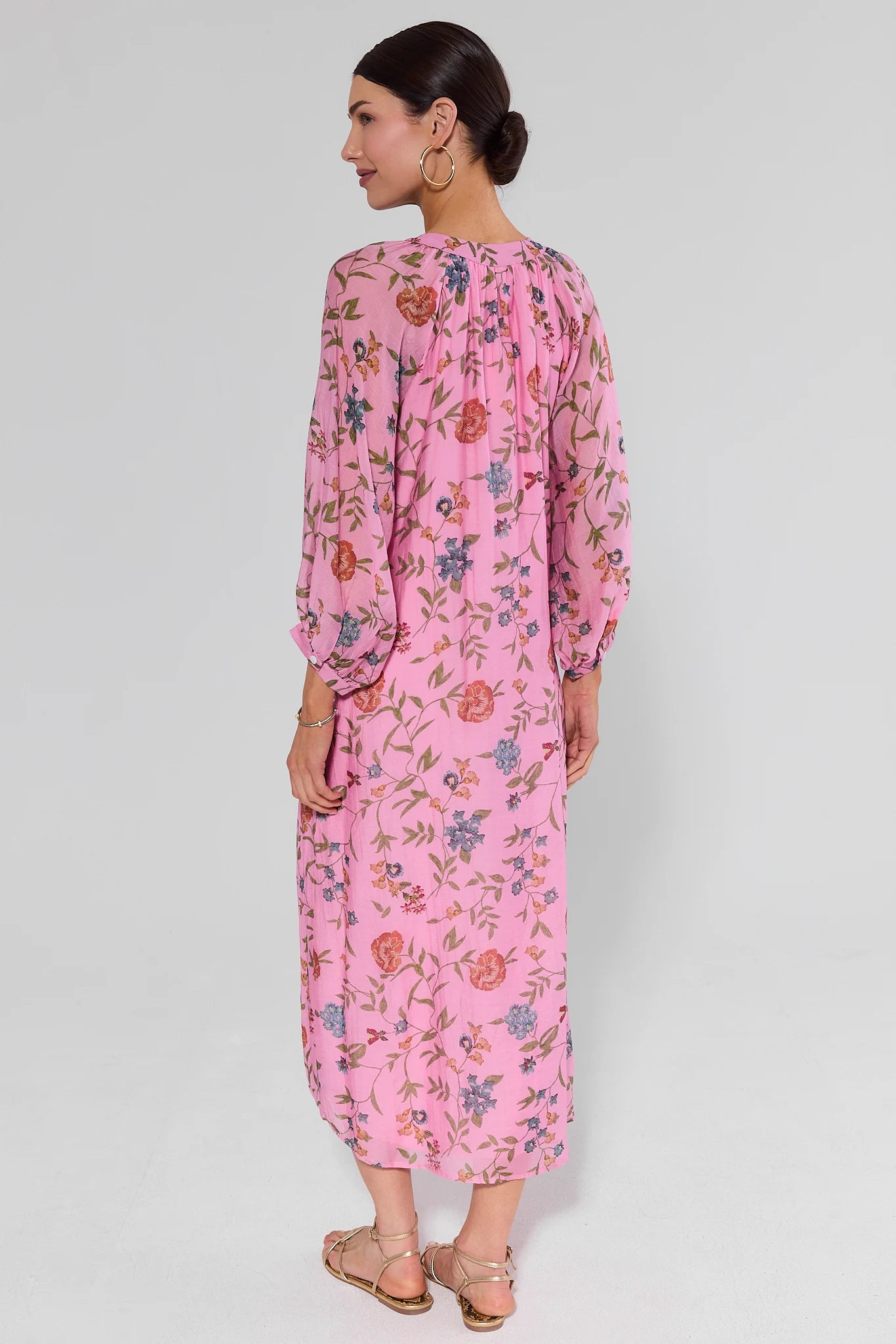 Woman standing wearing a pink floral dress on a white background