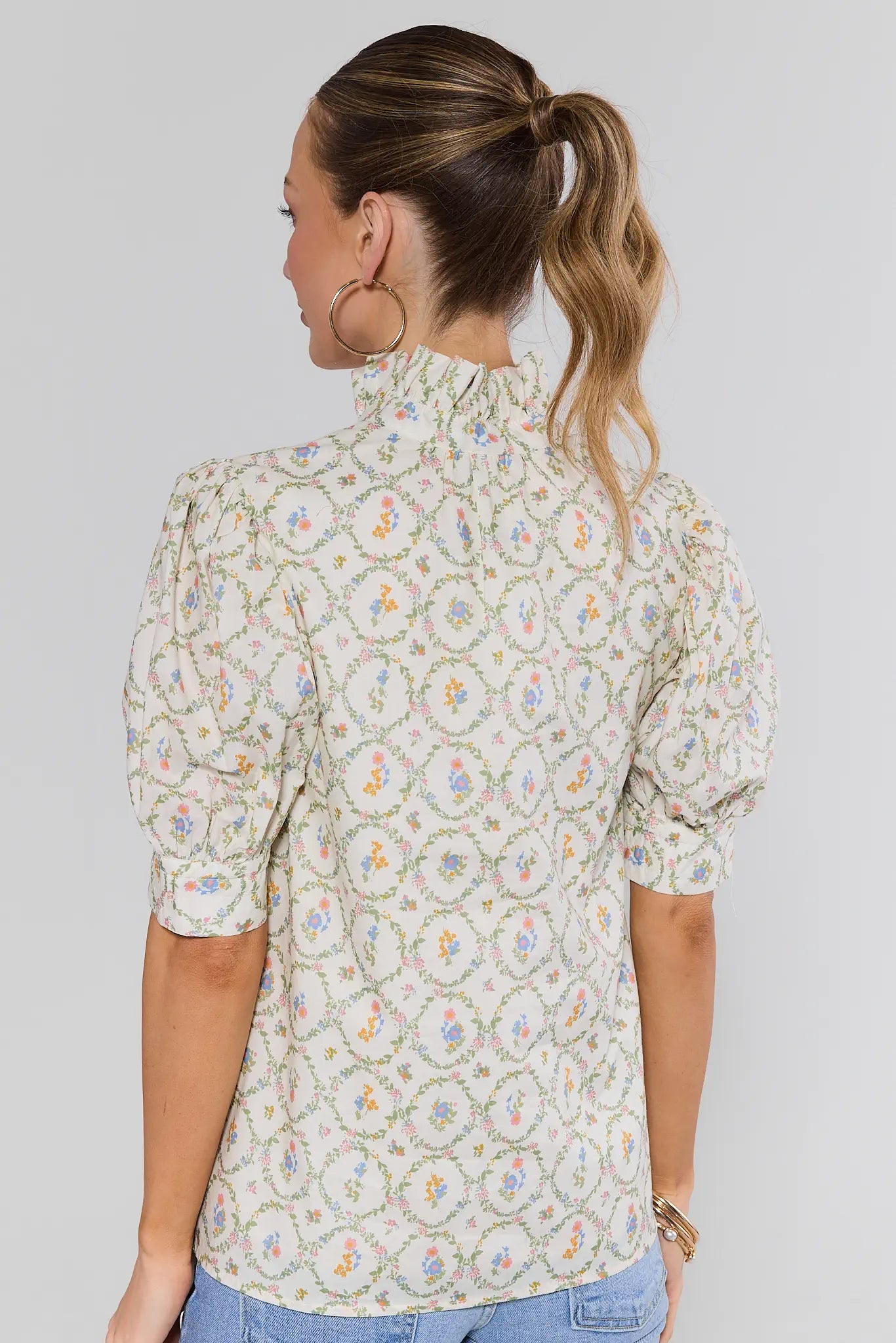 Woman wearing a floral patterned blouse by a plain background