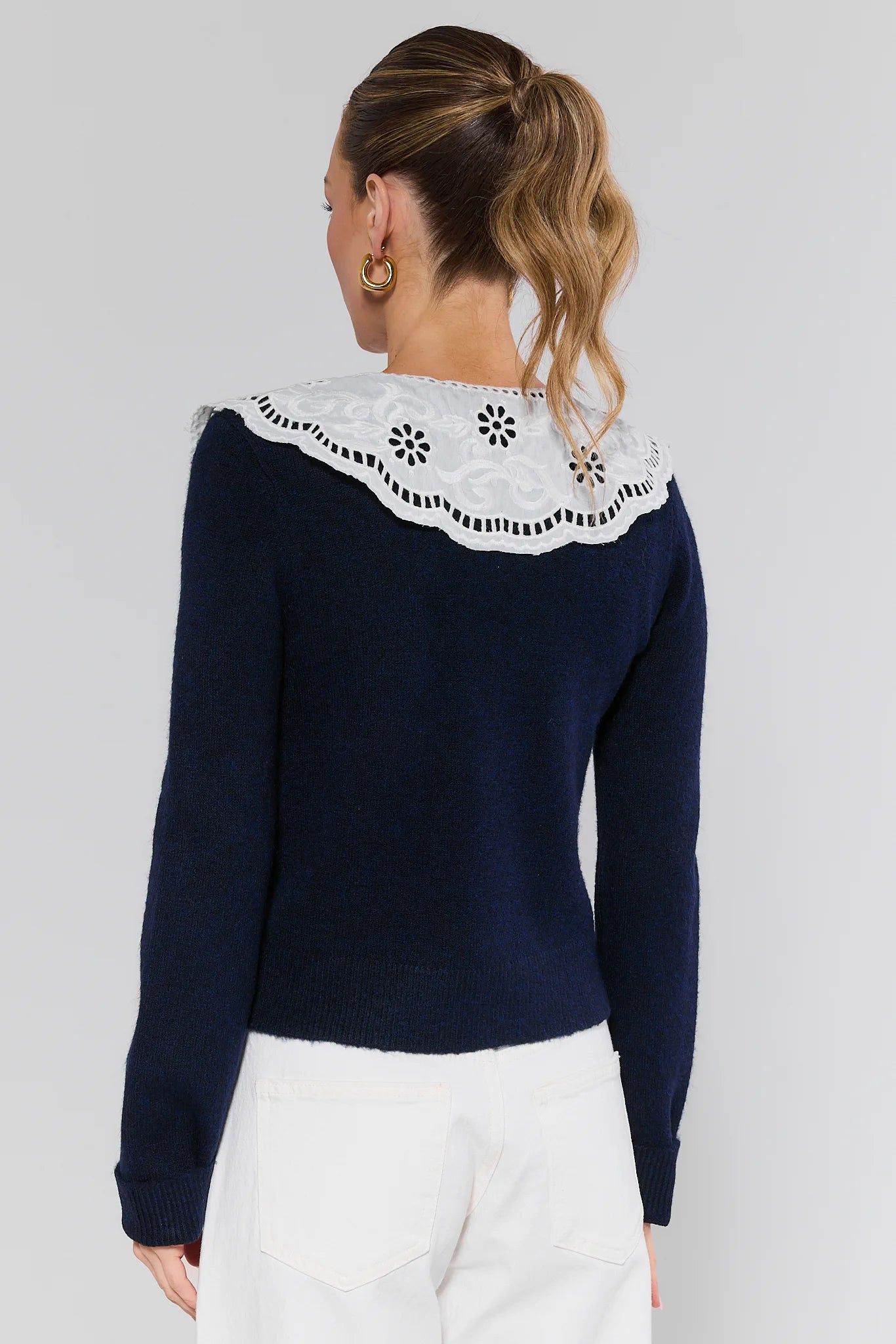 Navy sweater with white lace collar worn by a person on a plain background