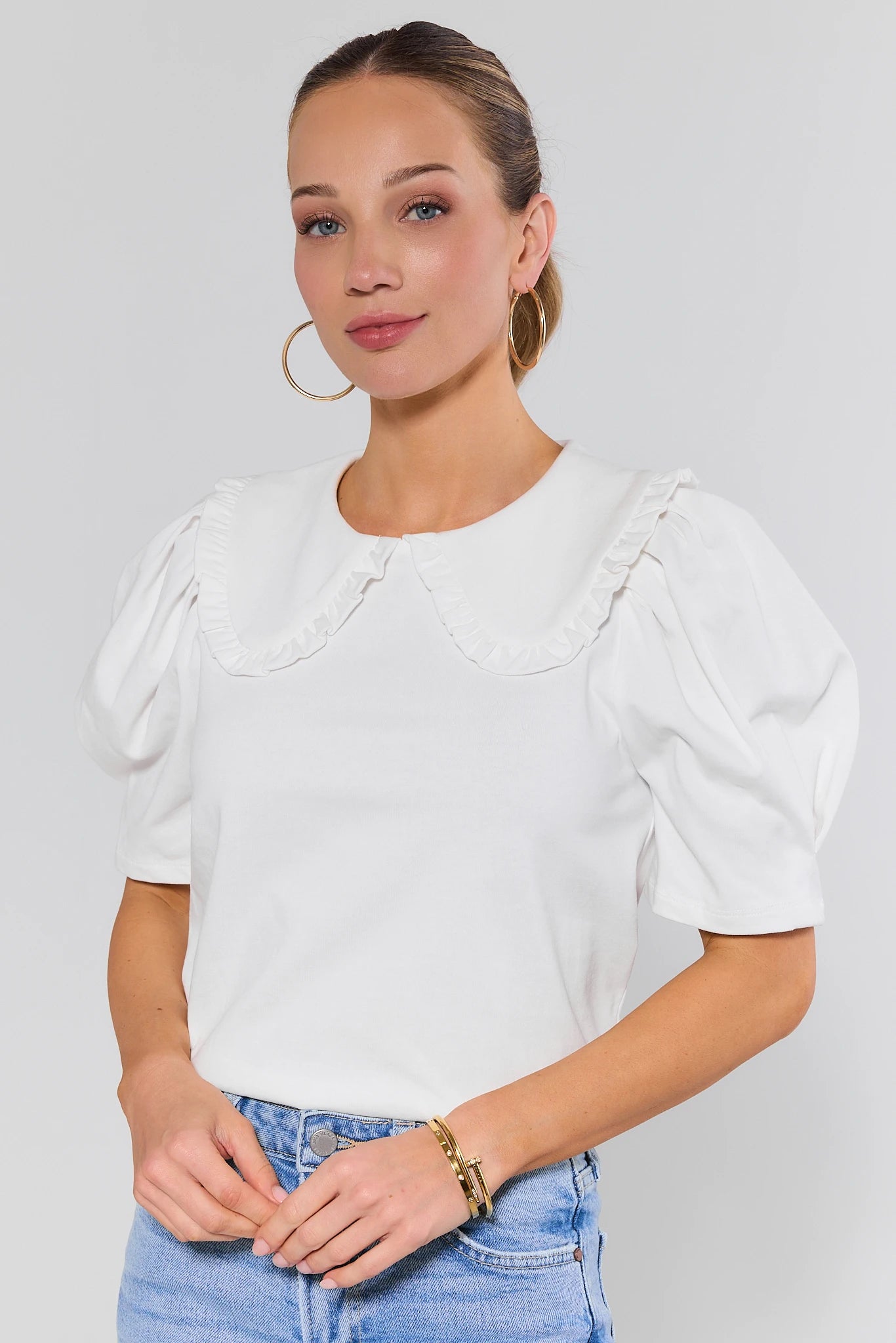Woman wearing a white blouse with puff sleeves against a plain background