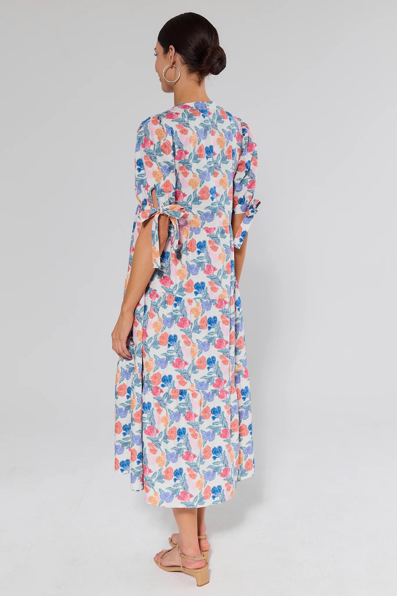 standing Woman wearing a floral dress against a plain background