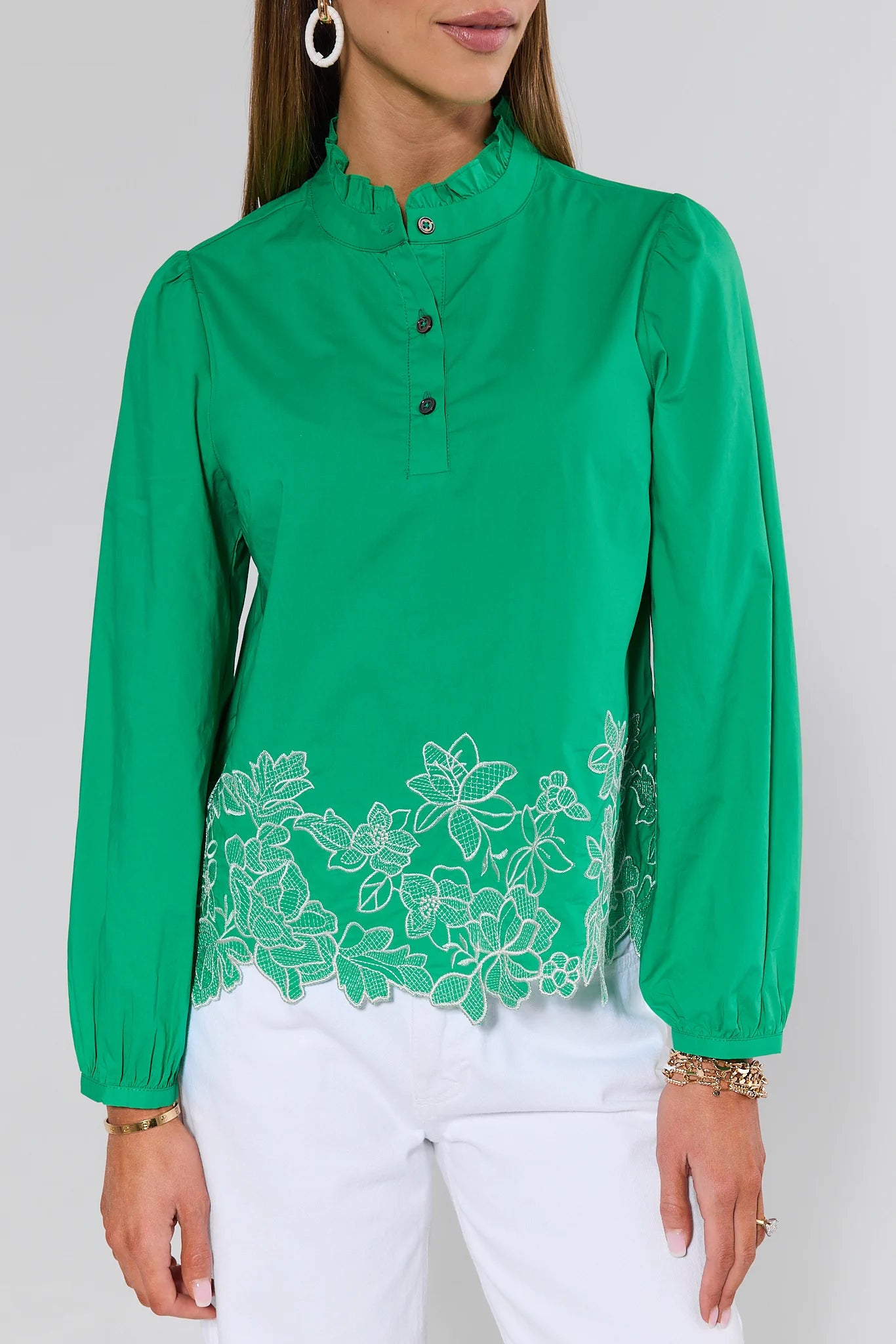 Green blouse with floral lace details worn by a person on a white background