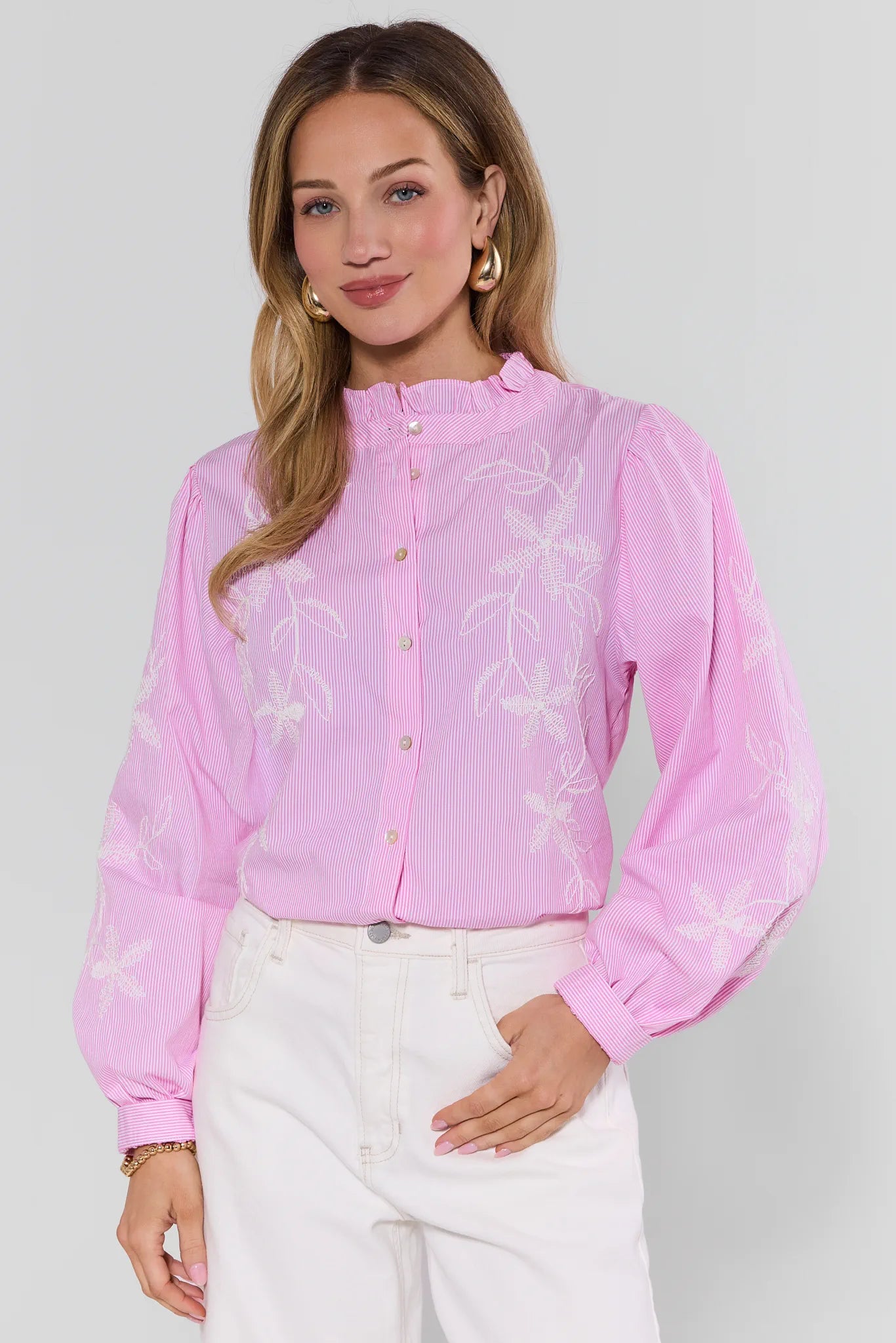 Woman wearing a pink blouse with floral patterns on a plain background