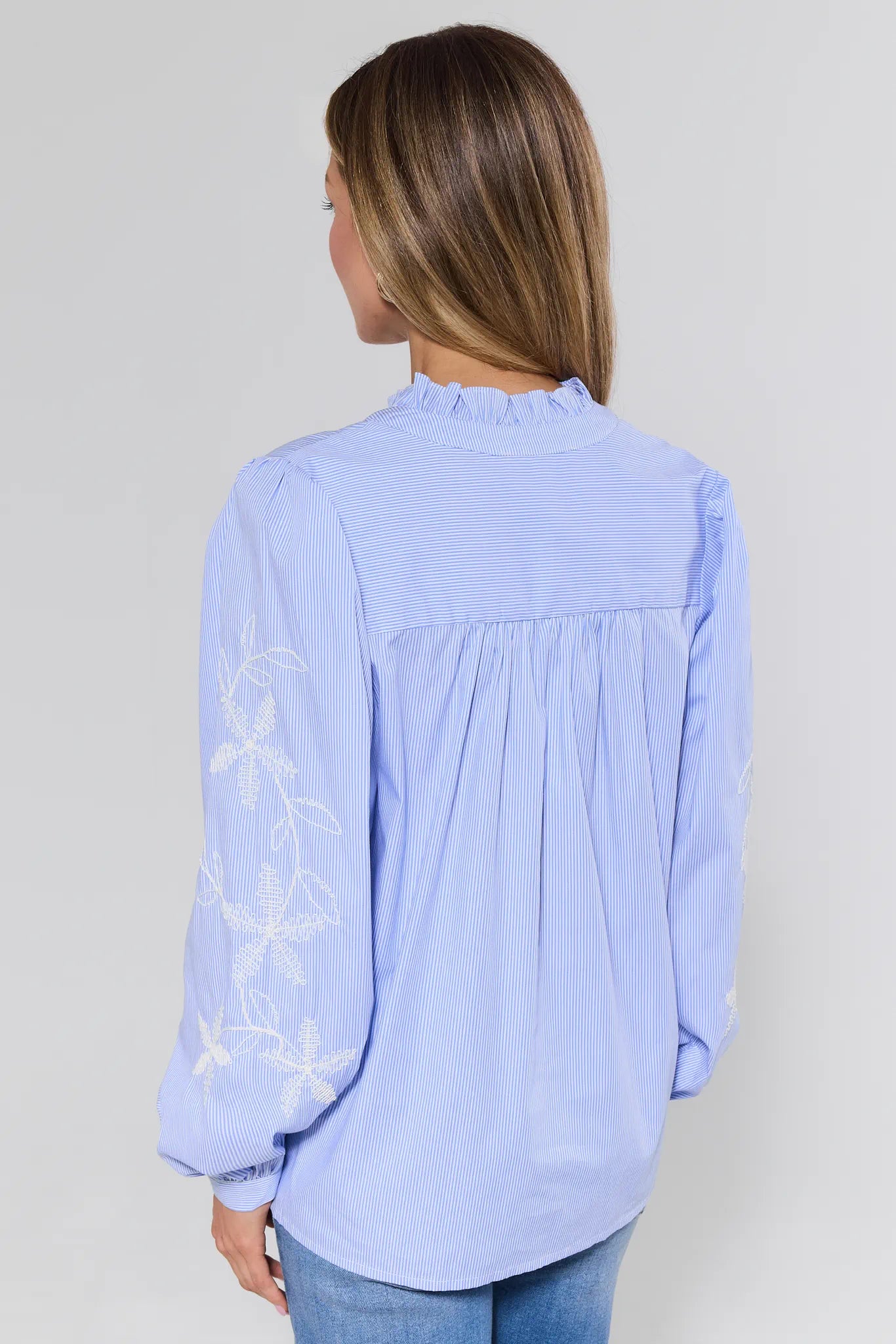 Light blue blouse with floral embroidery on a plain background