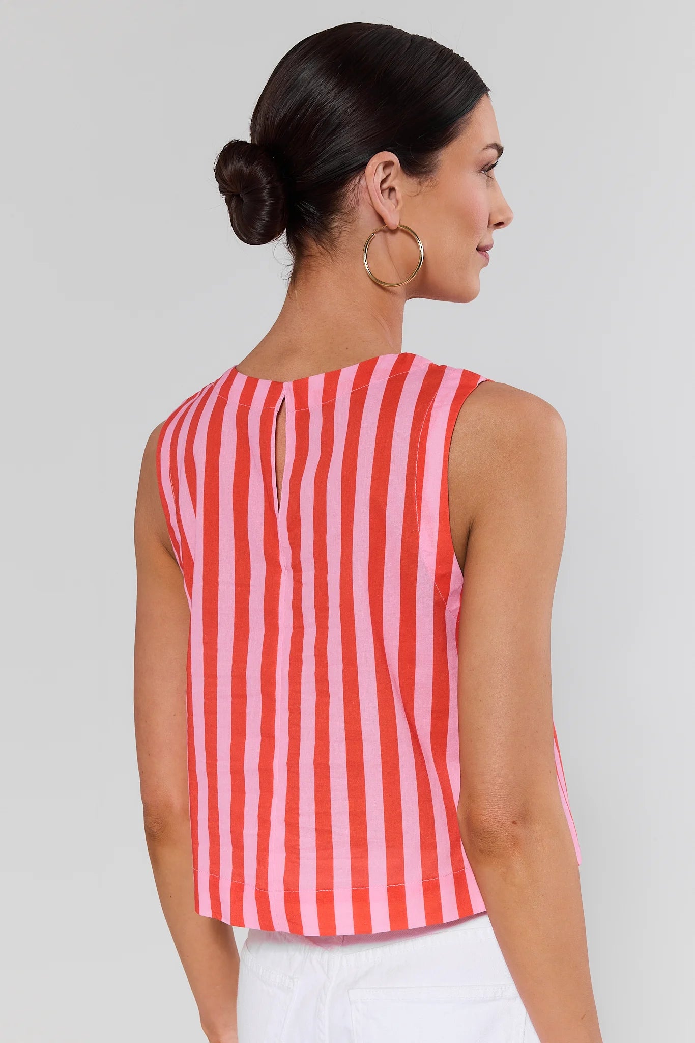 Woman standing wearing a red and white striped sleeveless top against a plain background