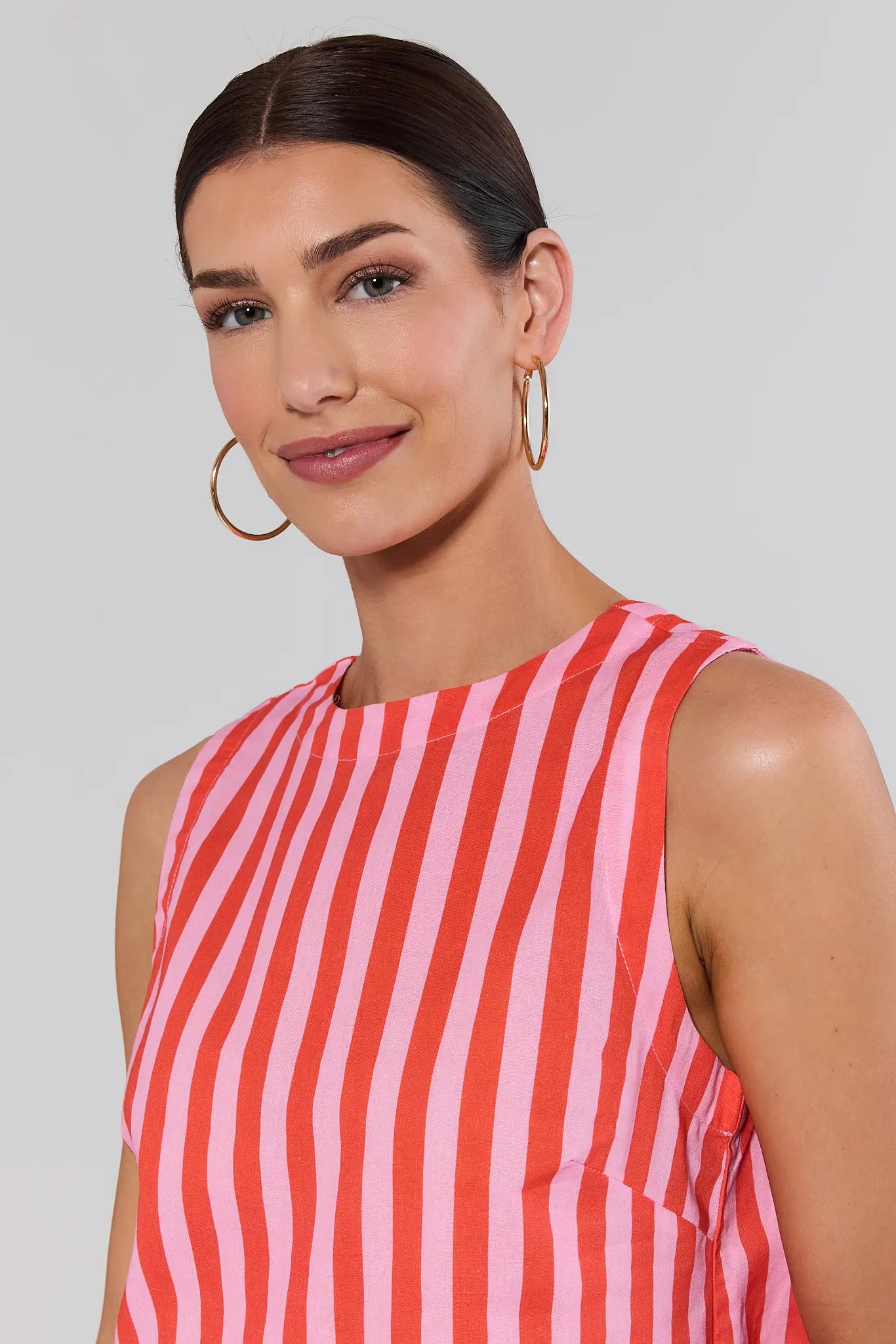 close up Woman wearing a red and white striped sleeveless top against a plain background