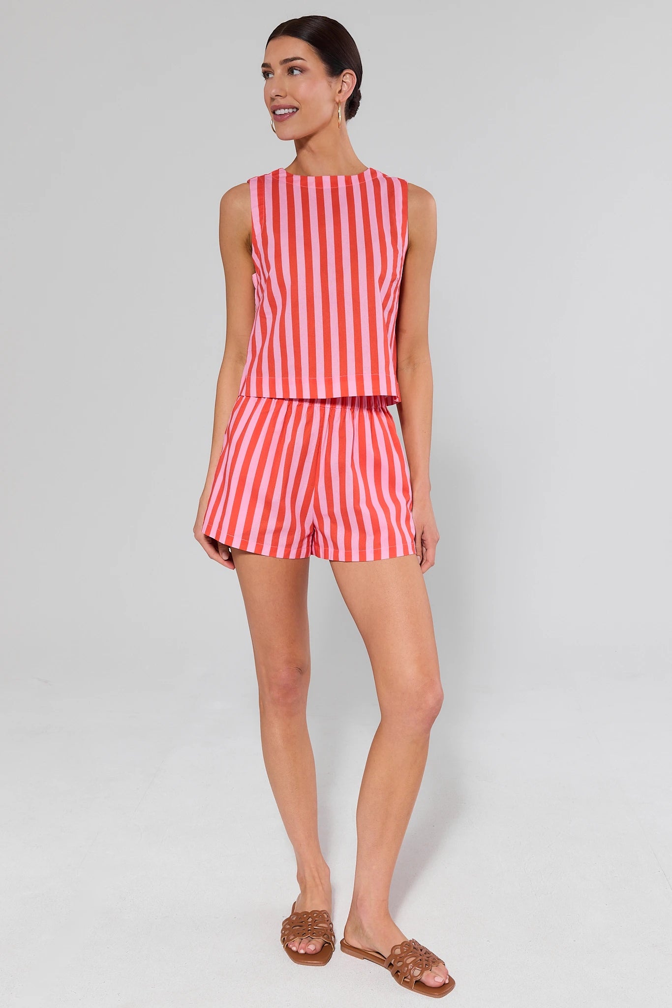Woman wearing a red and white striped outfit top and shorts on a gray background