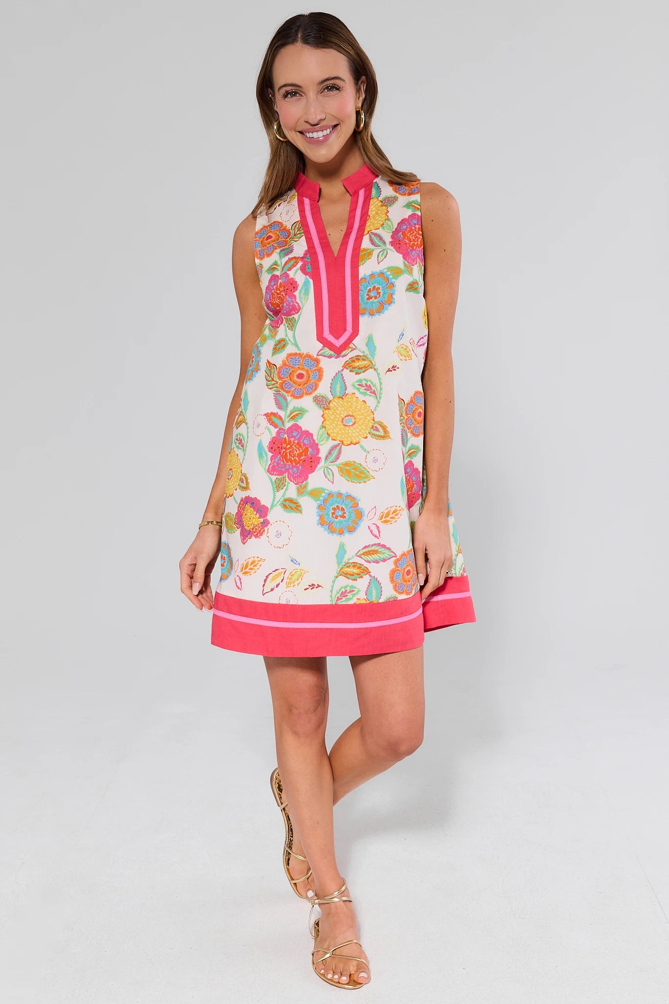 Woman standing wearing a colorful floral dress with a white background