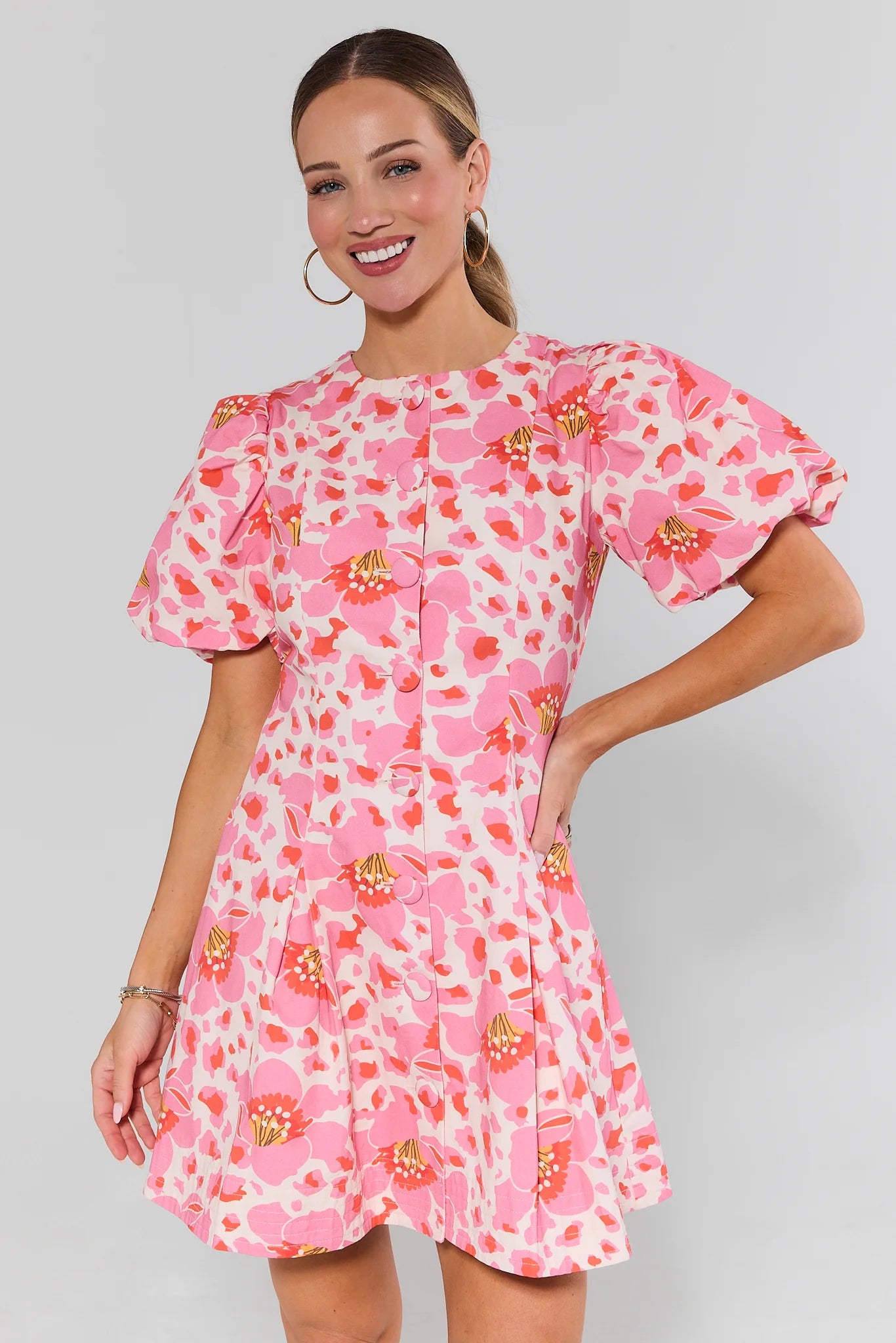 Woman wearing a pink floral dress against a gray background