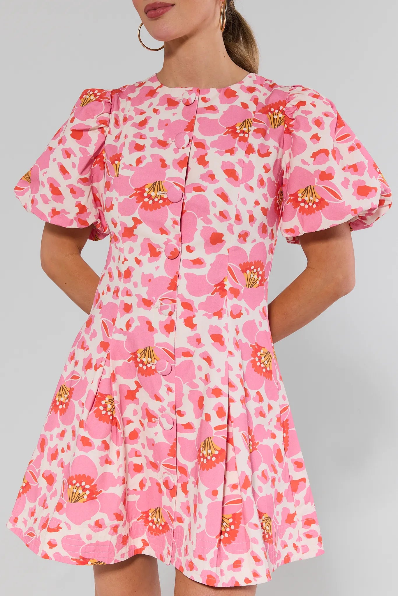 close up Woman wearing a pink floral dress against a gray background