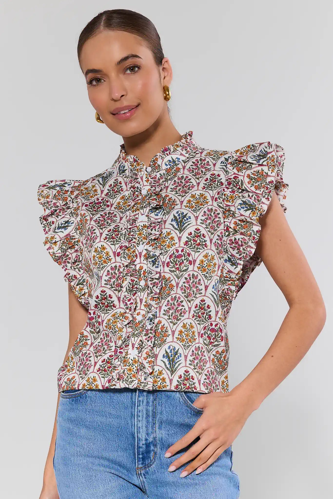 Woman wearing a floral blouse with ruffled sleeves against a plain background