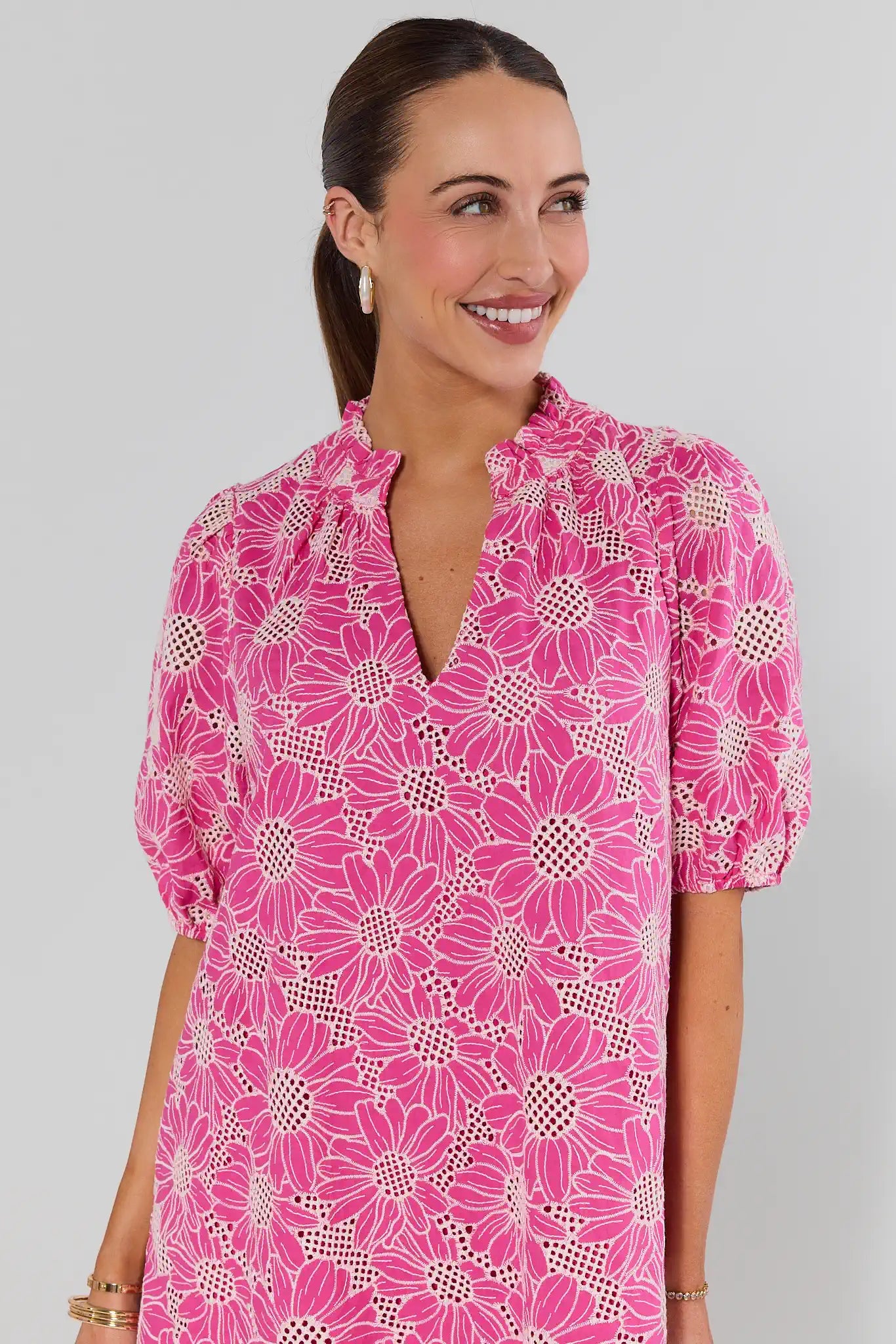 Woman wearing a pink floral dress against a gray background