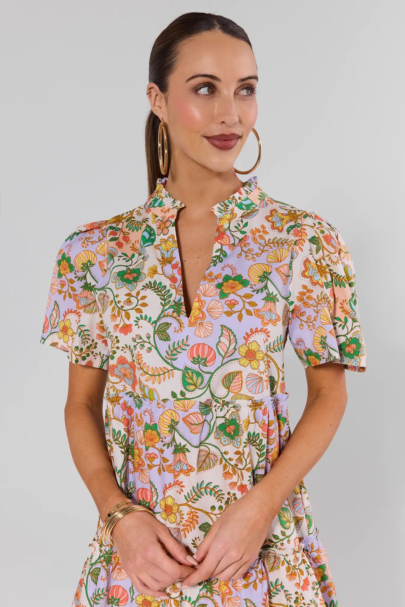 Woman wearing a colorful floral dress against a plain background