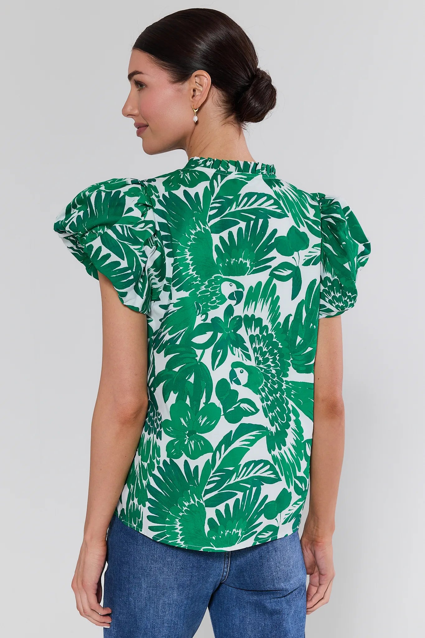 Woman wearing a green leaf-patterned top against a white background