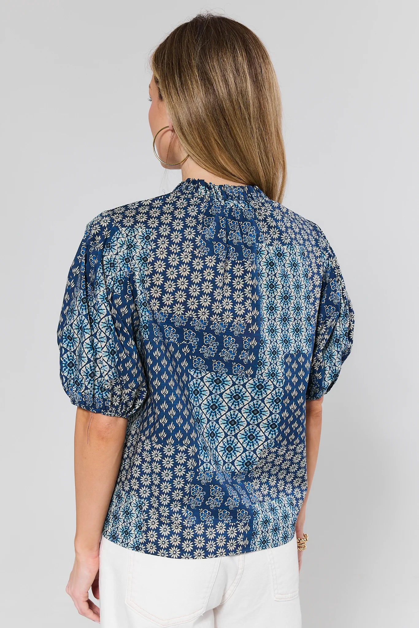 Woman wearing a blue patterned blouse against a gray background