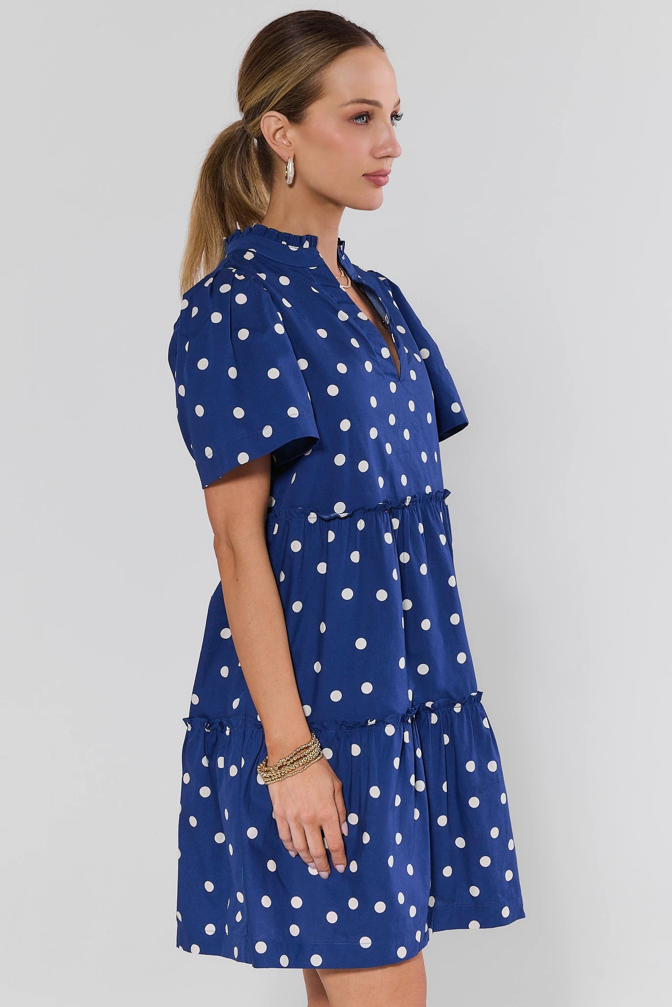 Woman wearing a blue dress with white polka dots on a light background