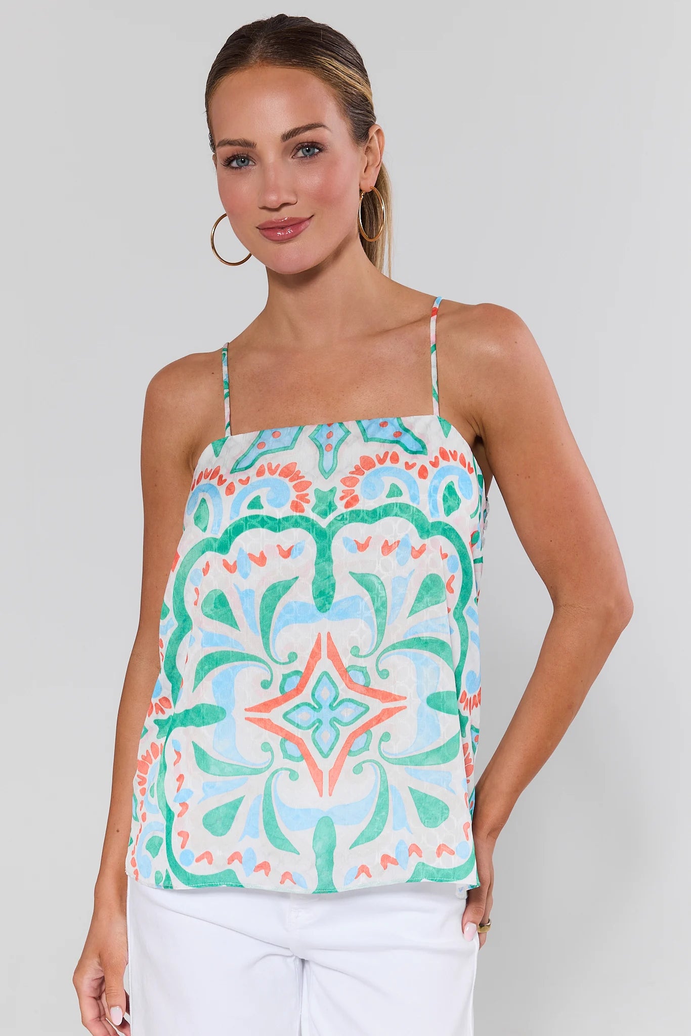 Woman wearing a colorful patterned tank top against a plain background