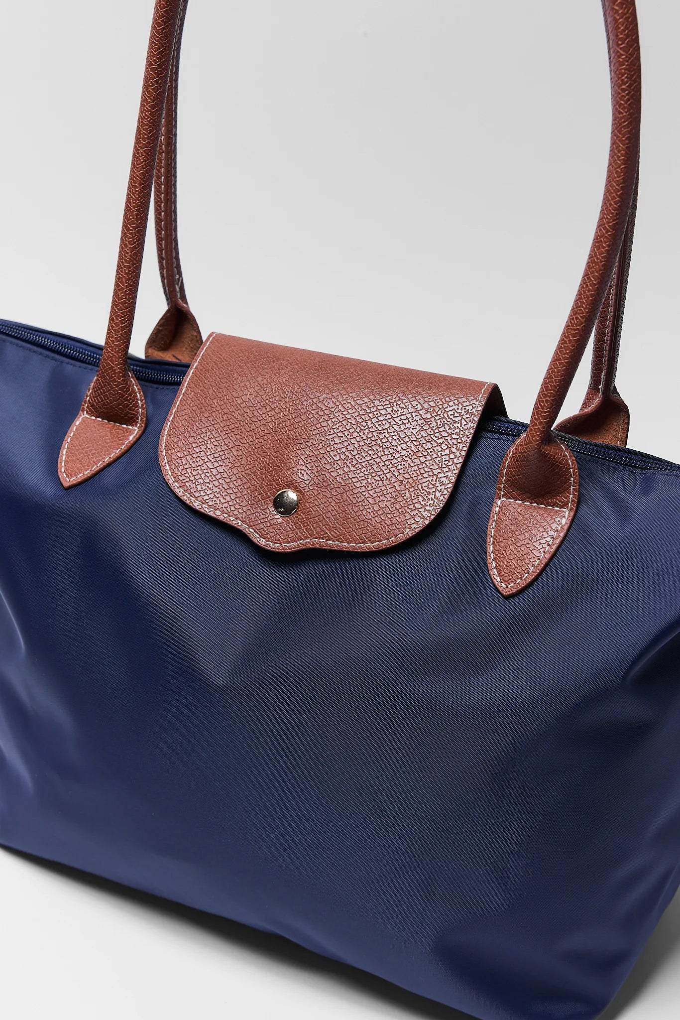 close up of navy tote bag on white background