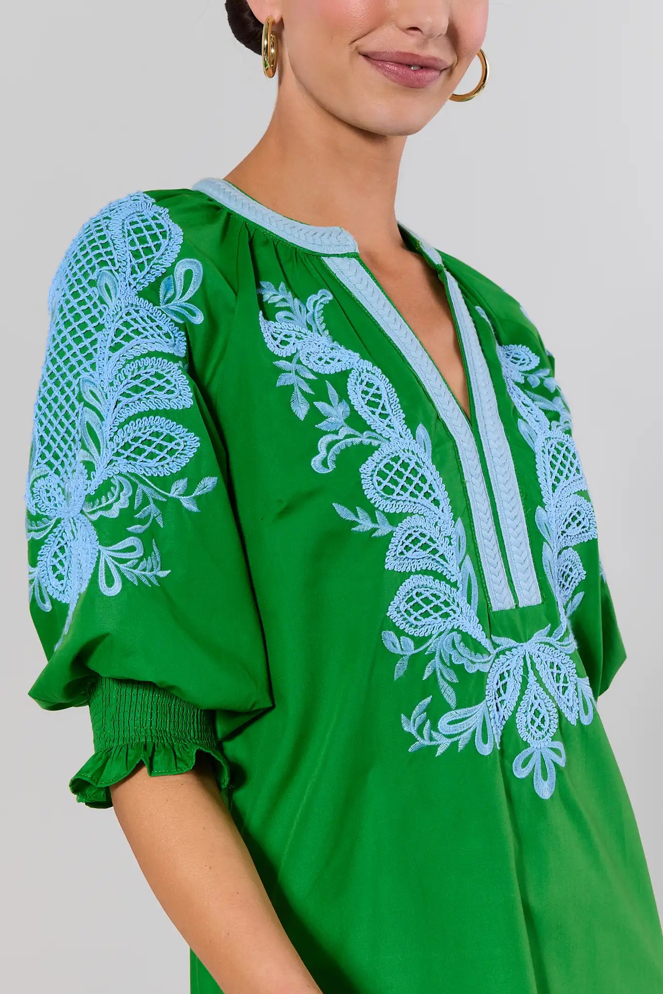 close up Green dress with white lace embroidery on a plain background