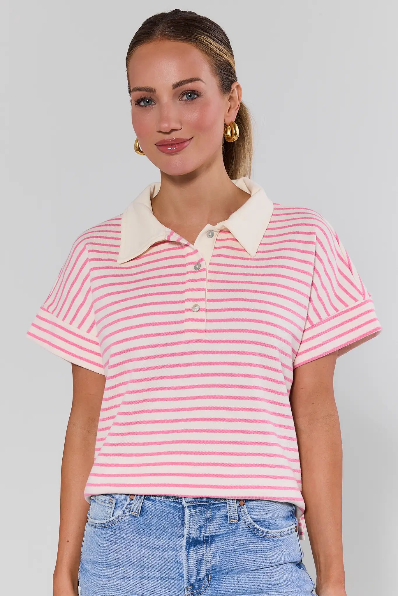 Woman wearing a pink and white striped polo shirt with a plain background