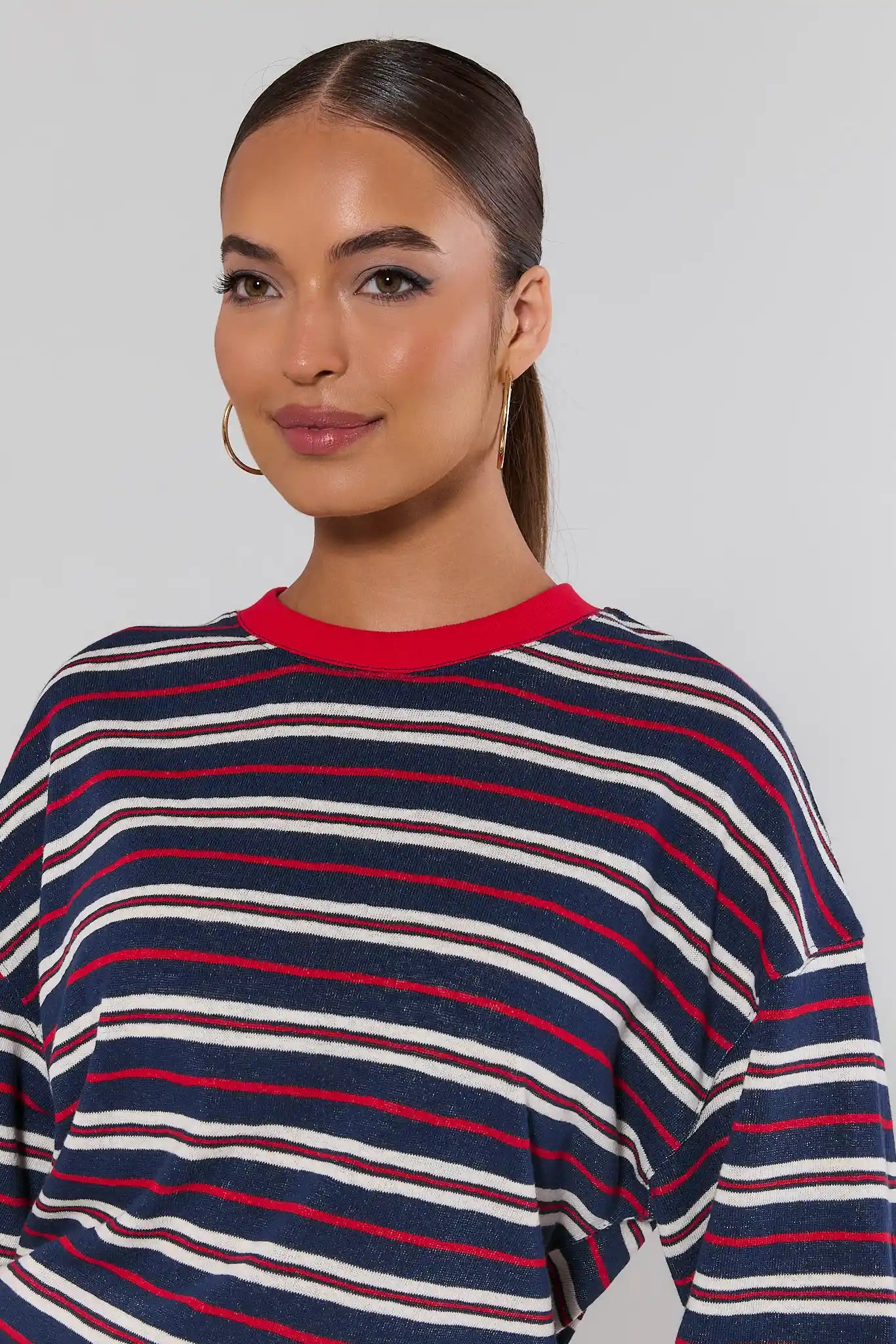 close up Woman wearing a striped sweater with red, white, and blue horizontal stripes on a plain background