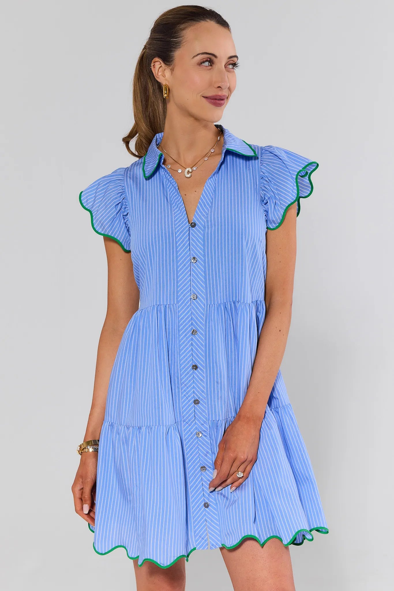 Woman wearing a blue striped dress with green trim on a plain background