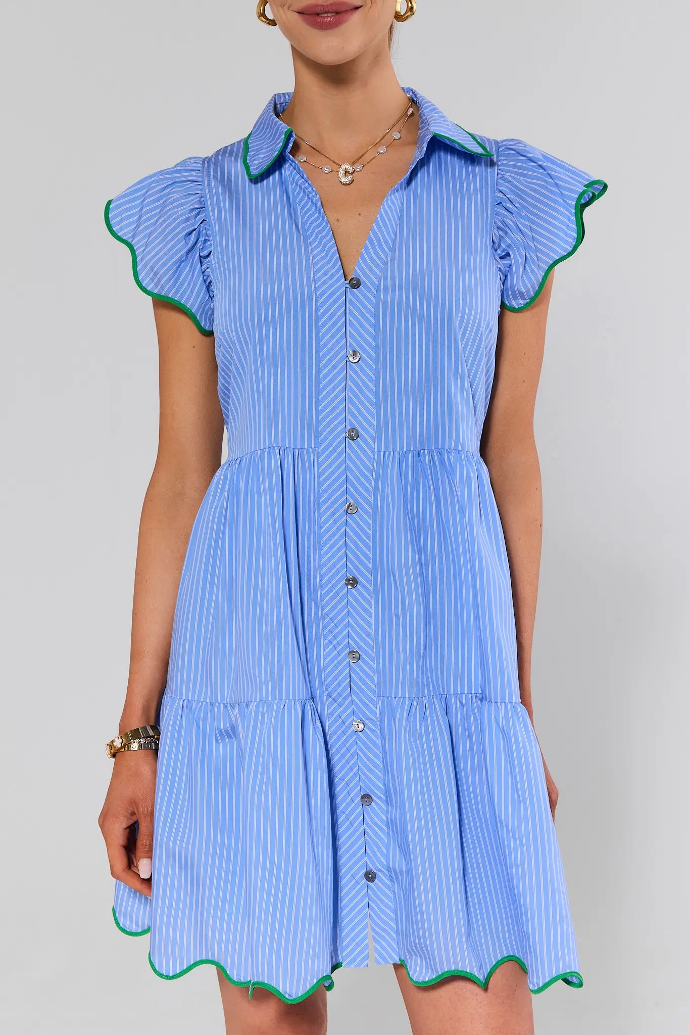 close up Woman wearing a blue striped dress with green trim on a gray background