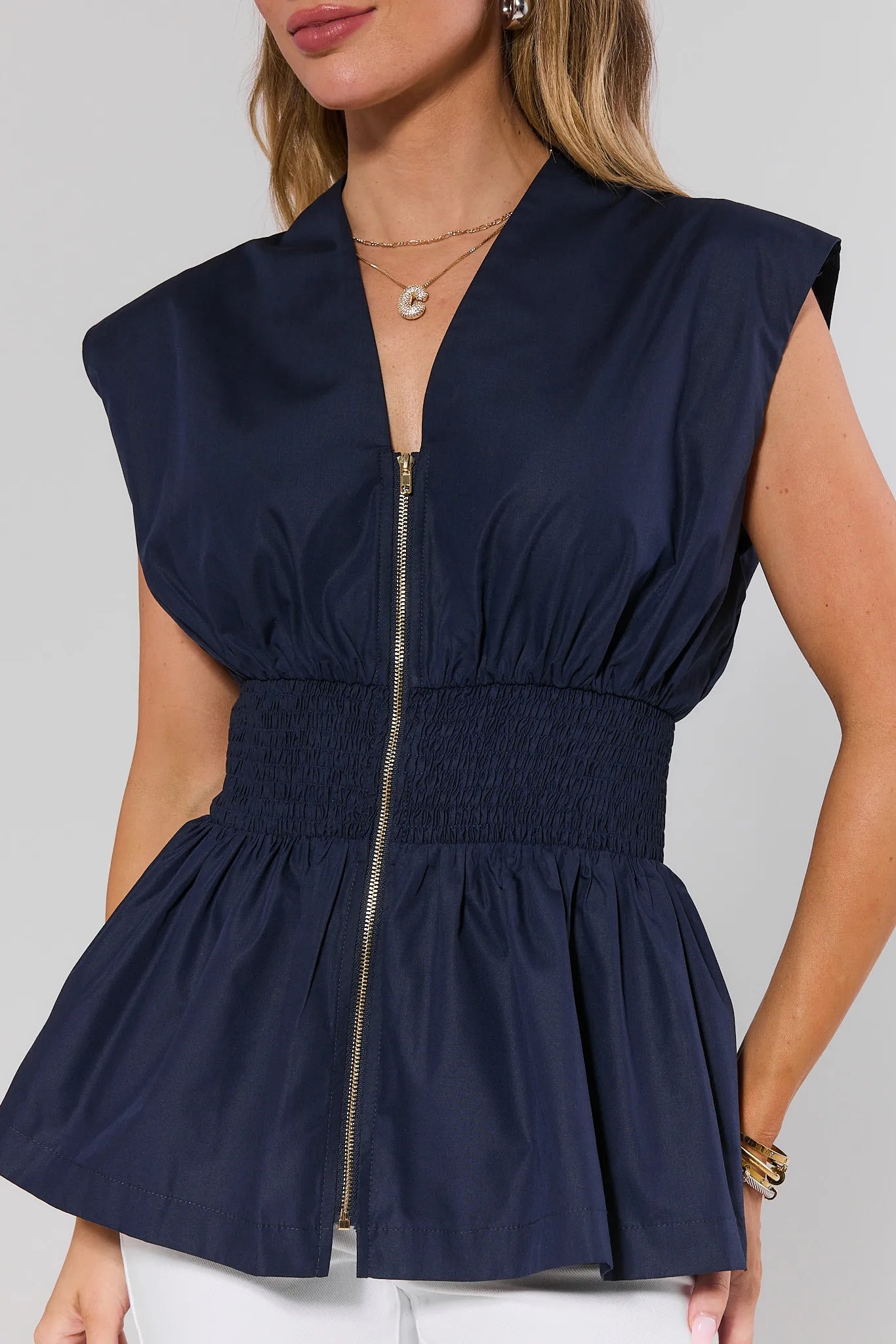 close up Navy blue peplum top worn by a person on a plain background