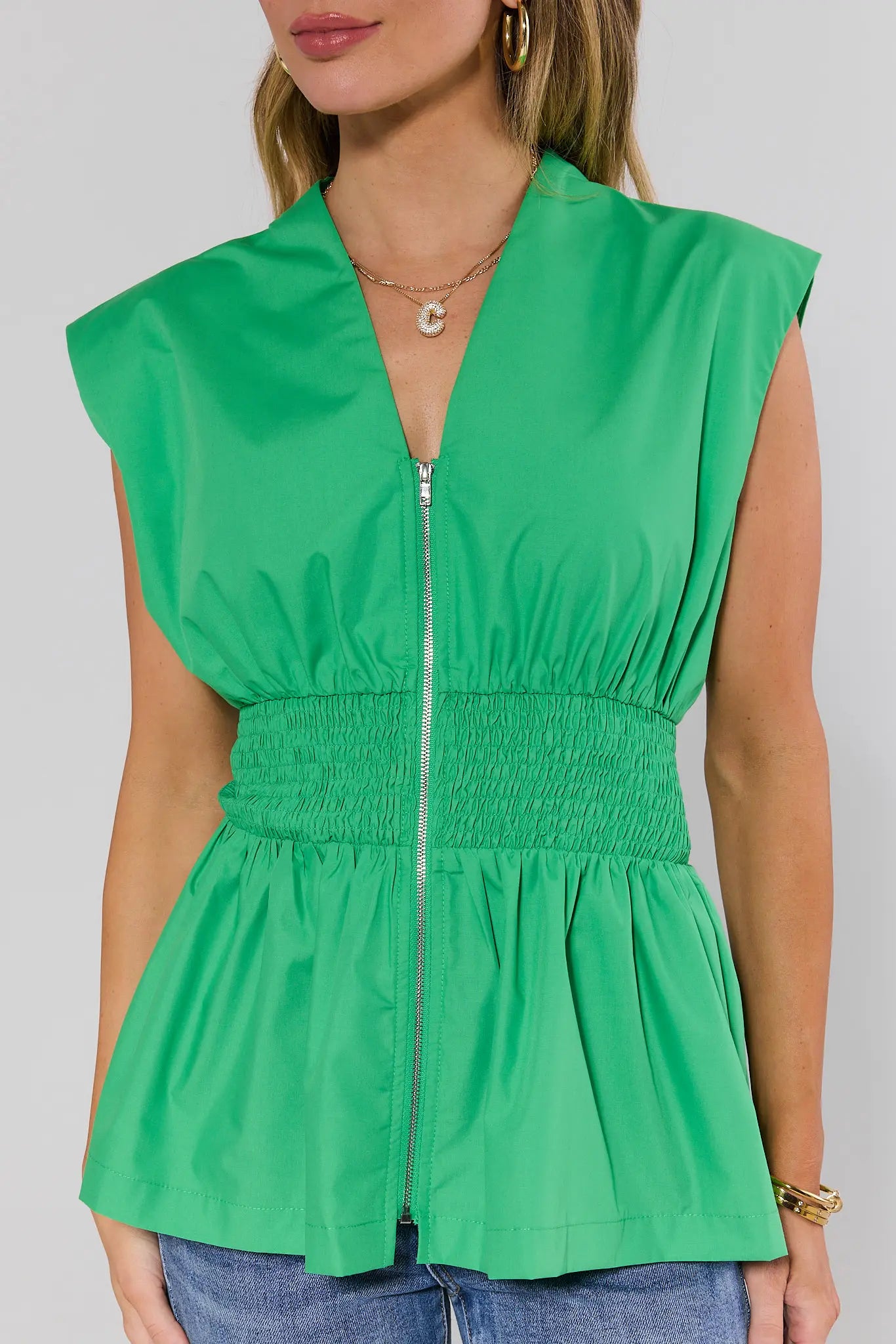 close up Green sleeveless top with zipper on a plain background